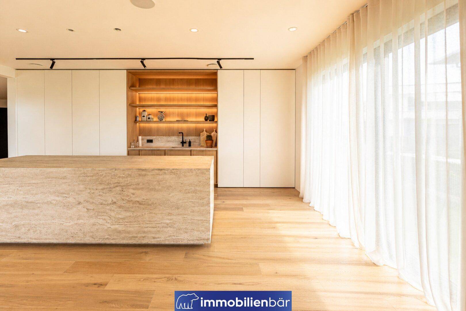 Moderne Küche mit großer Kücheninsel, integrierten Schränken und hellem Fensterbereich.