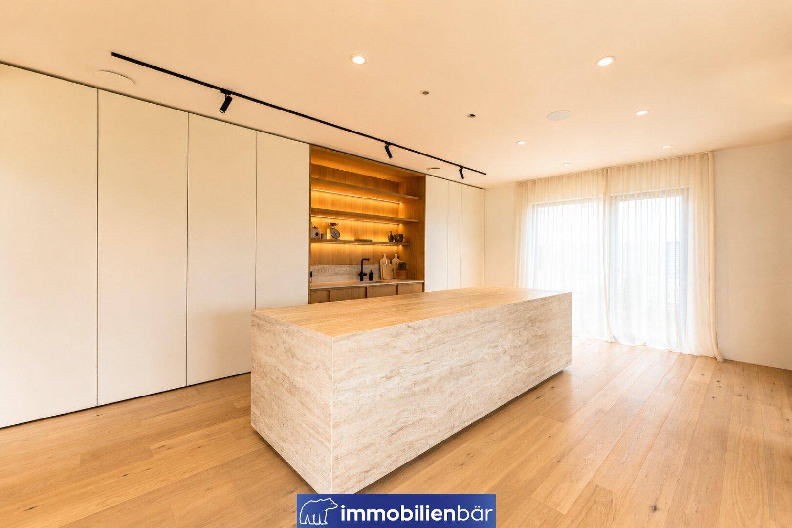 Geräumige moderne Küche mit großer Steininsel und minimalistischen Einbauschränken.