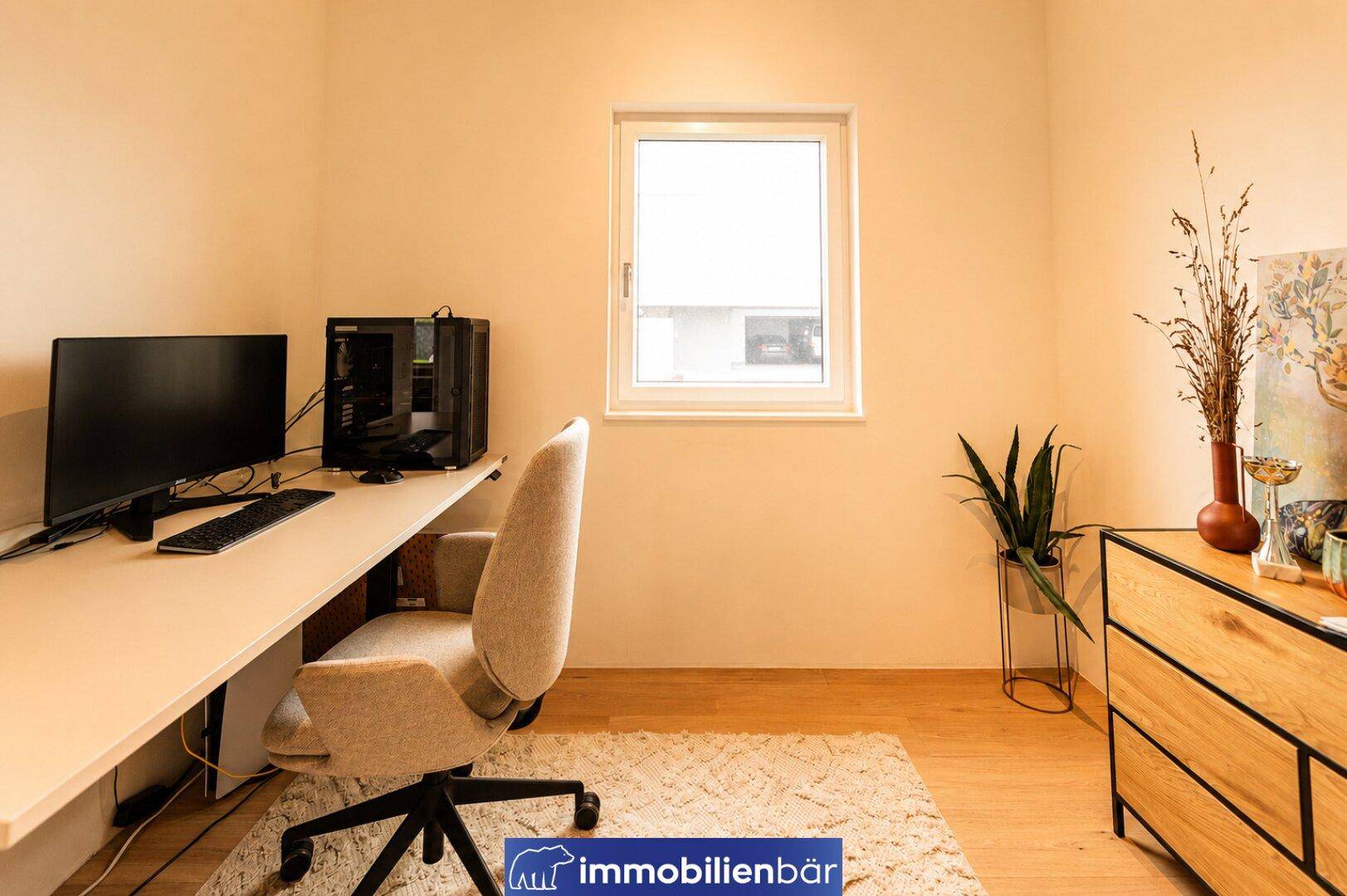Funktionales Büro mit Schreibtisch, Computer und Fenster für ausreichend Tageslicht.