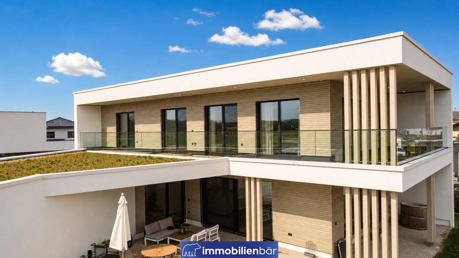 Ansicht des modernen Hauses von oben mit Gründach, Balkonen und einer Terrasse.