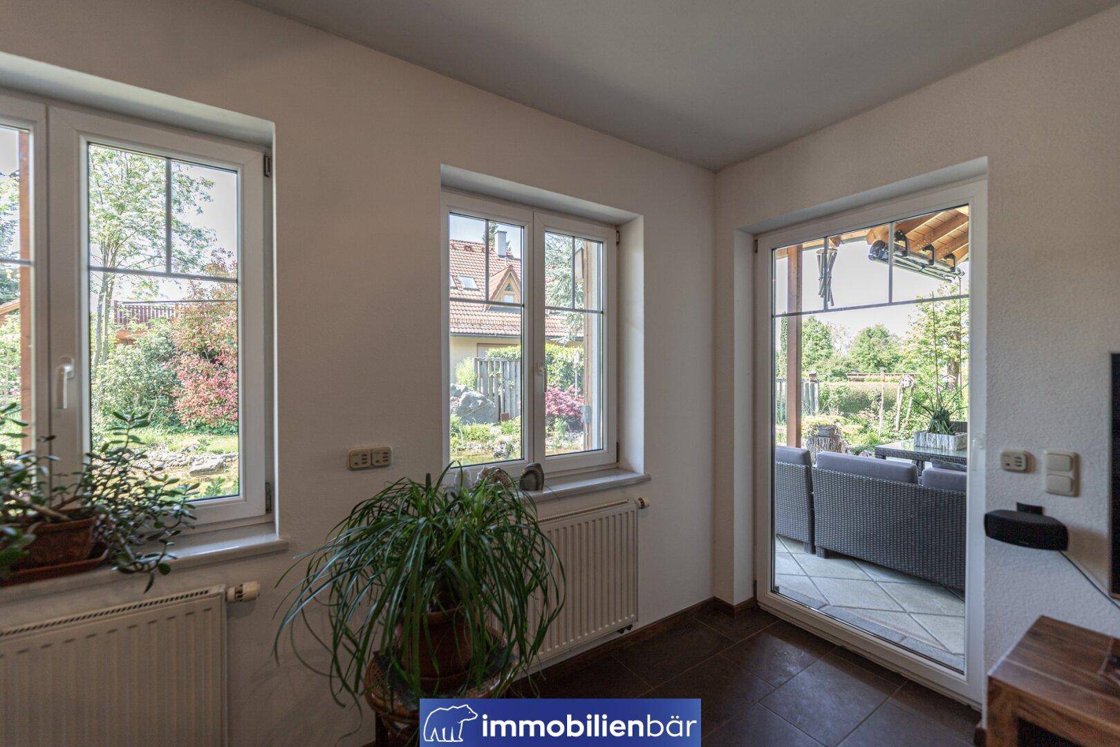Heller Raum mit großen Fenstern und direktem Zugang zur Terrasse und zum Garten.