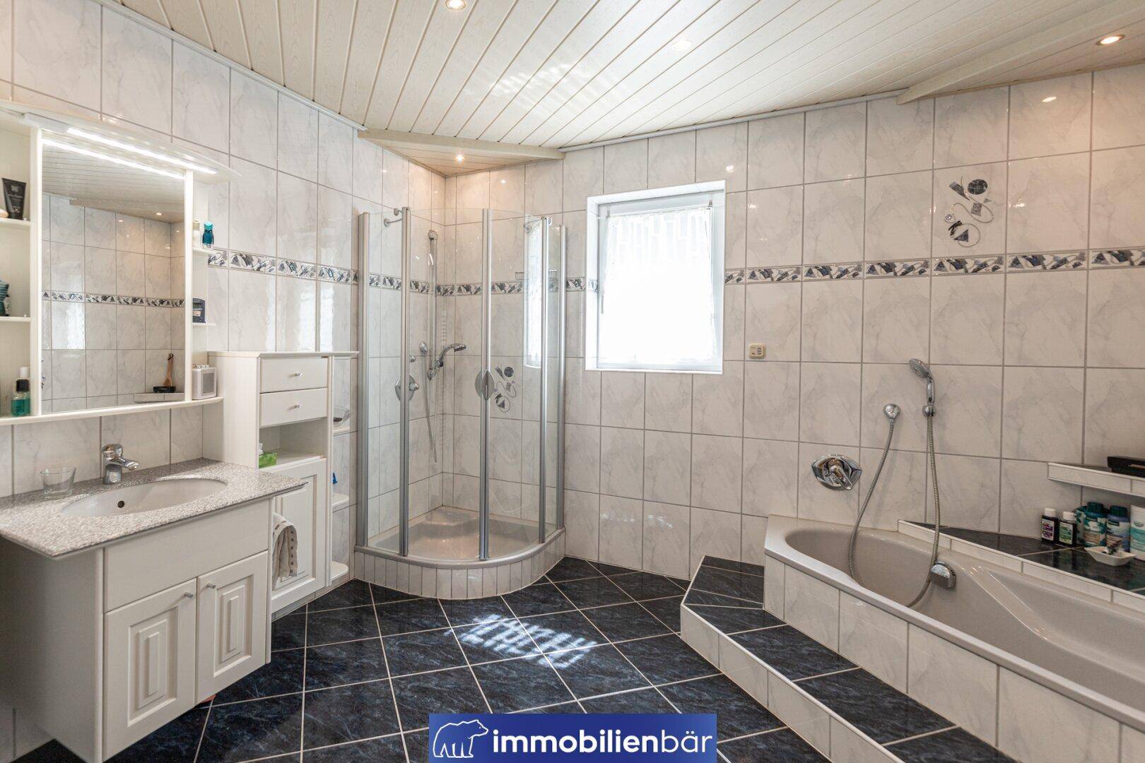 Geräumiges Badezimmer mit Eckdusche, Badewanne, Doppelwaschbecken und Fenster.