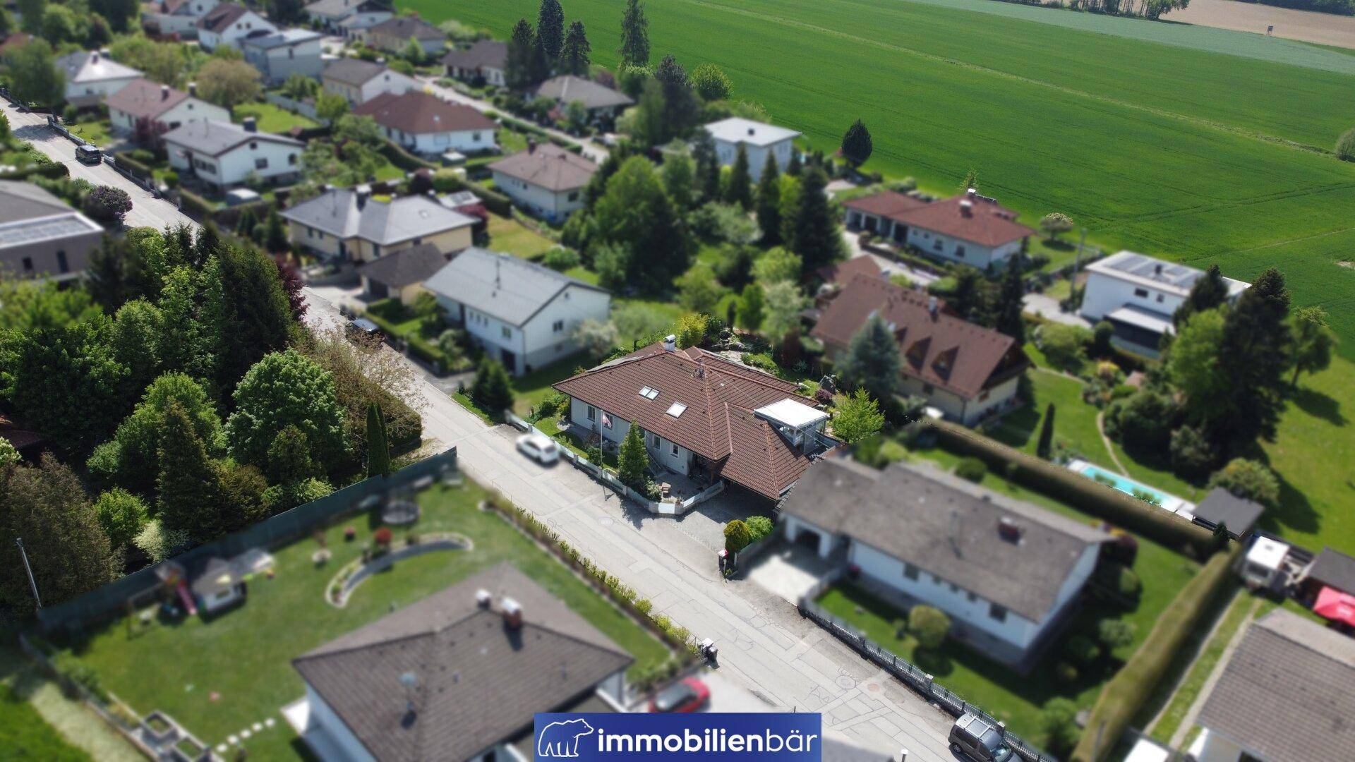 Weitläufige Luftaufnahme einer Wohnsiedlung mit Einfamilienhäusern und viel Grün.