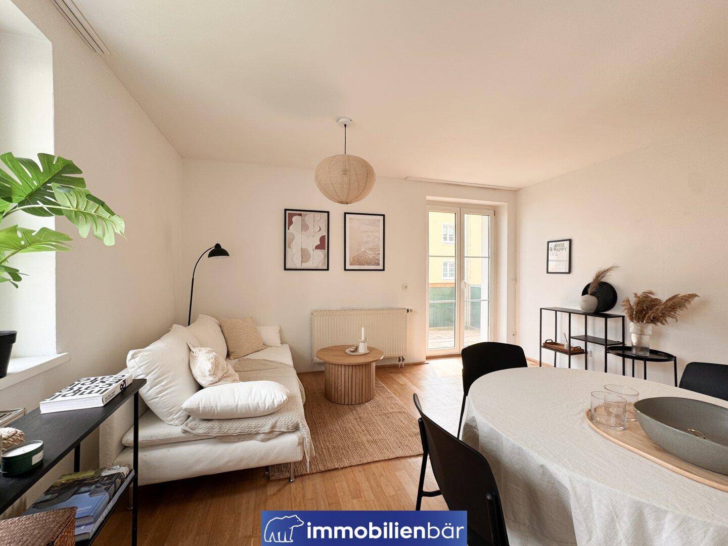Heller Wohn- und Essbereich mit Zugang zu einem Balkon und modernem Mobiliar.