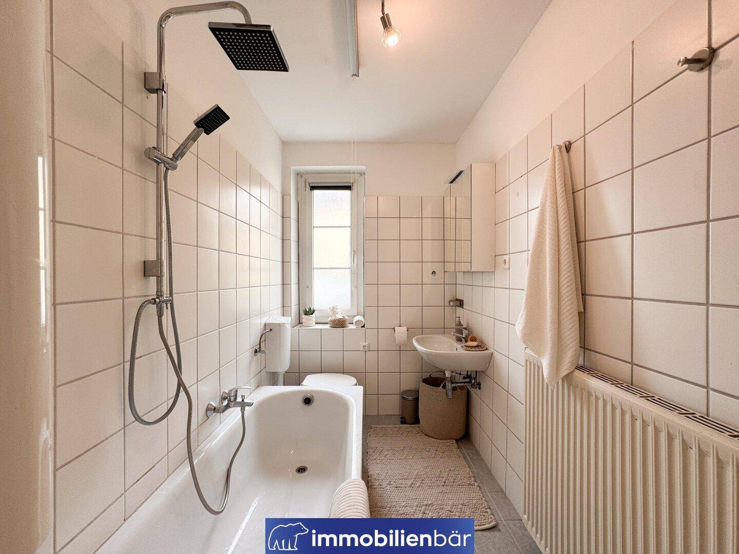 Funktionales Badezimmer mit Badewanne, Dusche, WC, Waschbecken und Fenster.