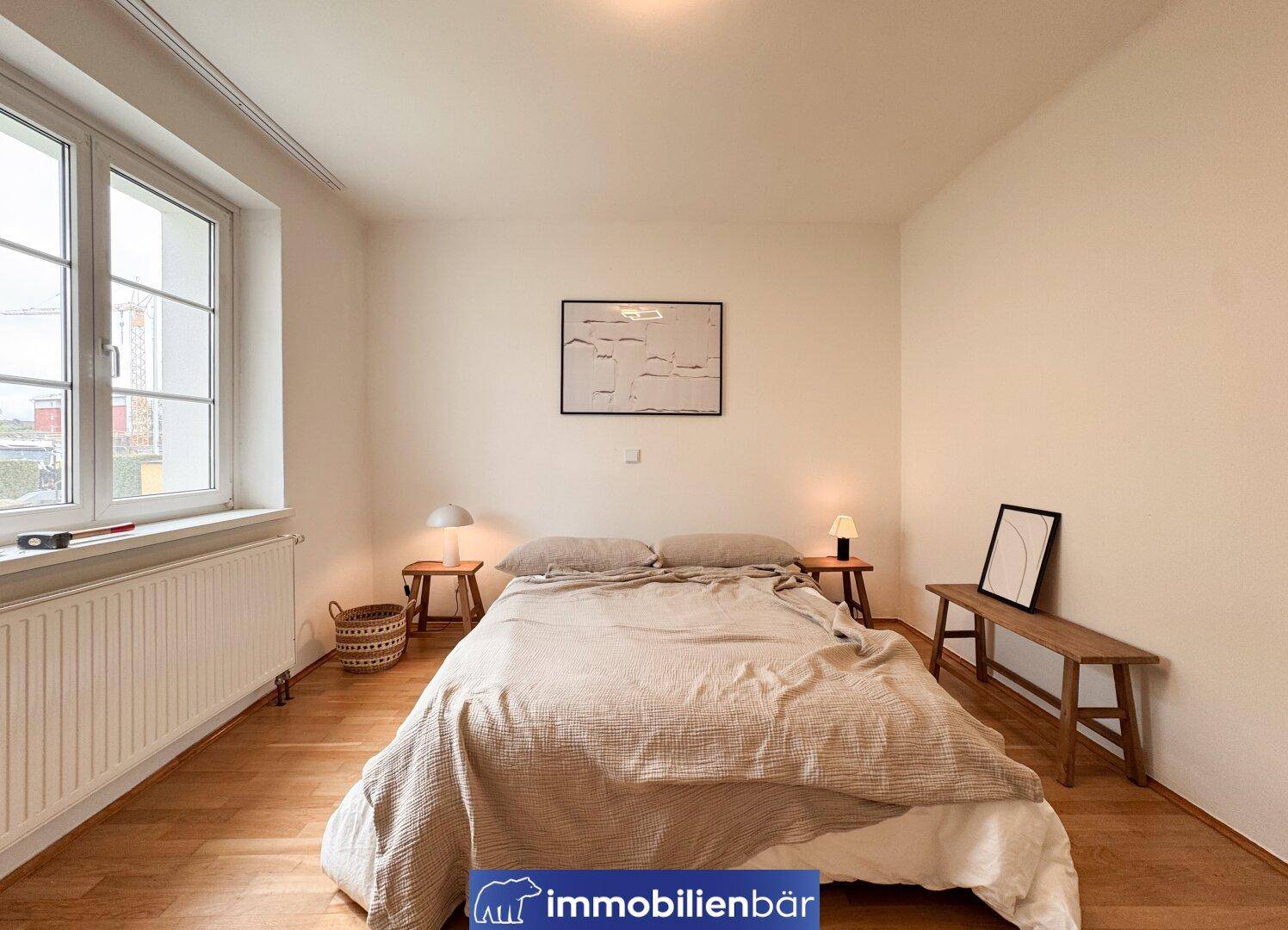 Geräumiges Schlafzimmer mit Doppelbett, Holzboden und großem Fenster für viel Tageslicht.