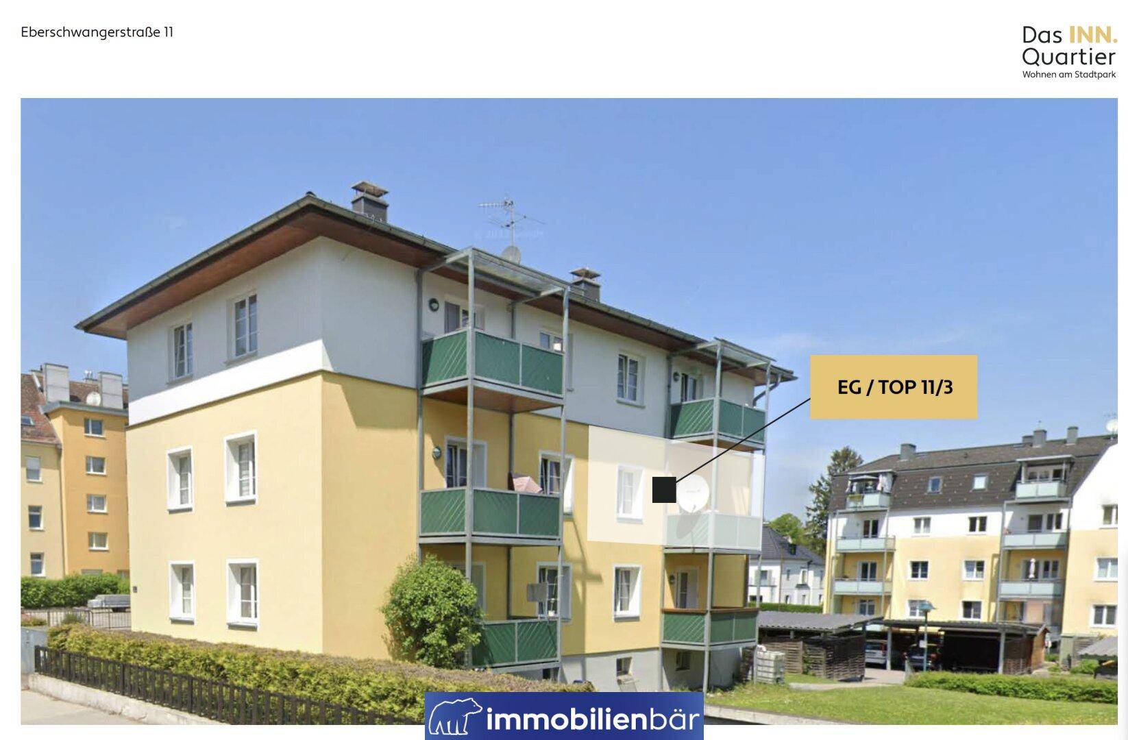 Mehrfamilienhaus mit gelber Fassade und grünen Balkonen in städtischer Umgebung.