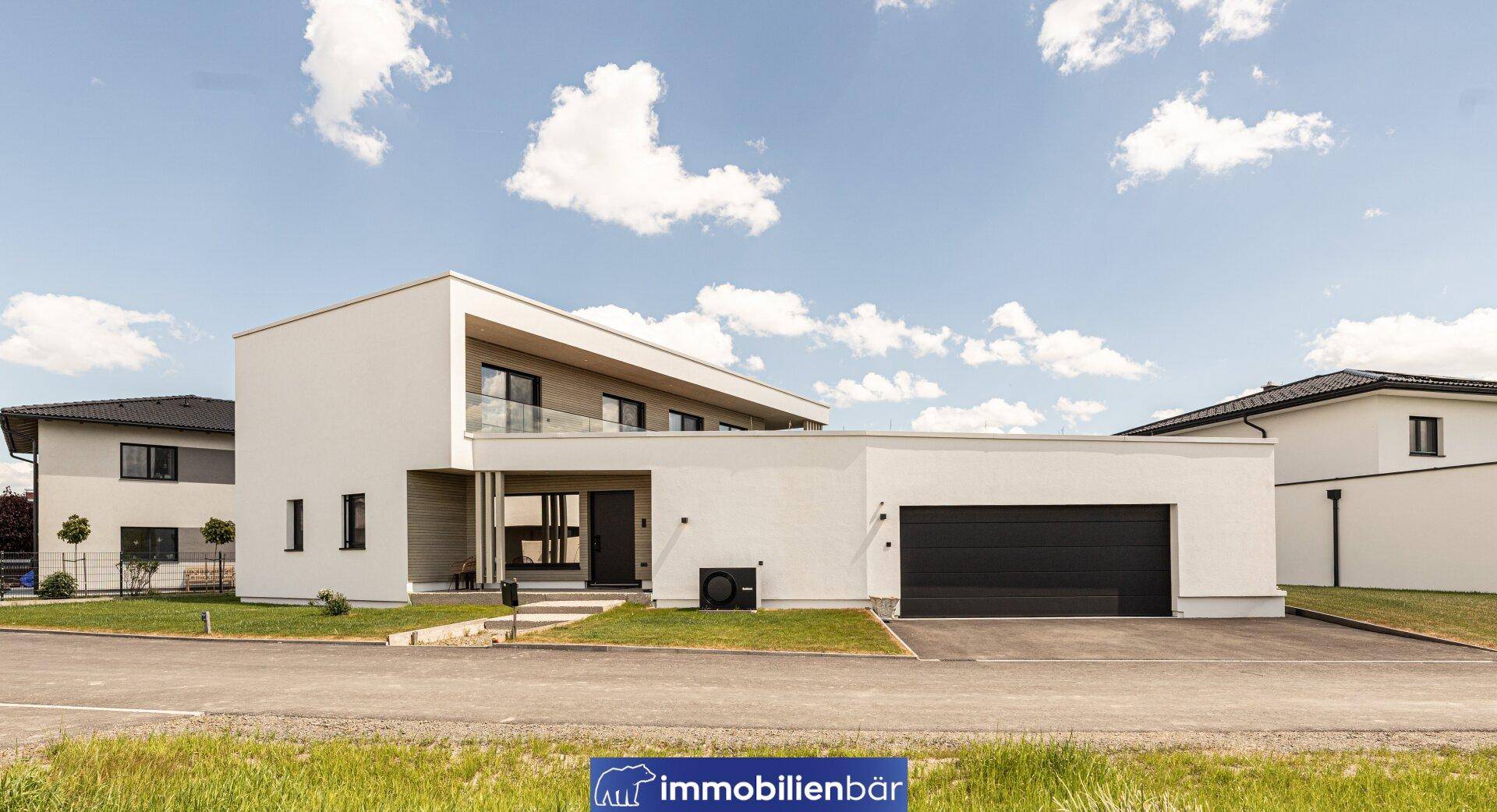 Moderne weiße Villa mit Flachdach und integrierter Garage unter blauem Himmel.