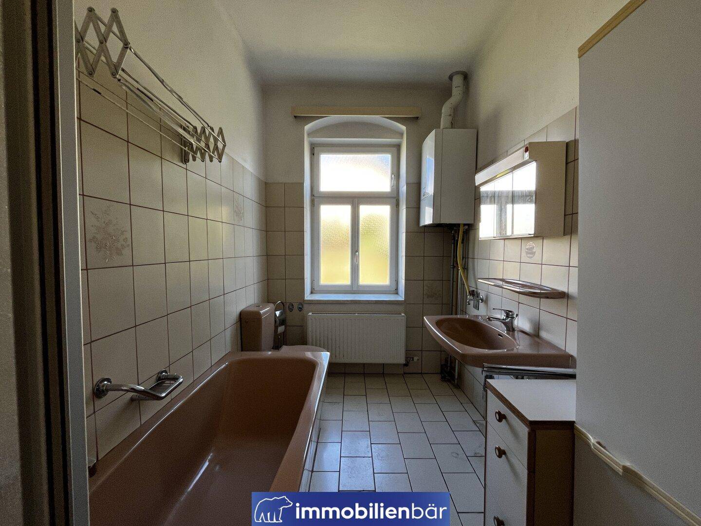 Badezimmer im 80er-Jahre-Stil mit brauner Badewanne, Fliesen und Fenster.