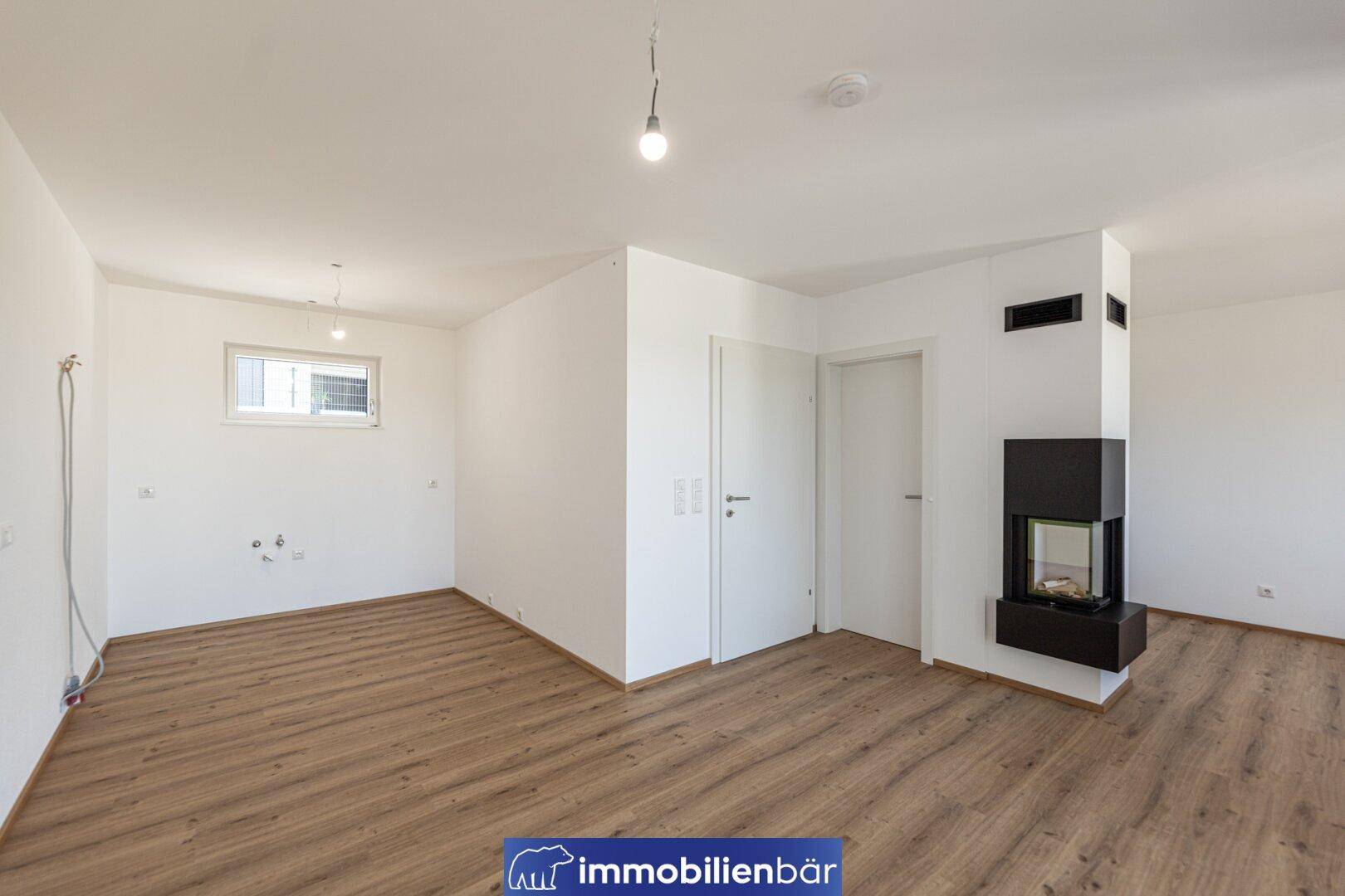 Offener Raum mit Laminatboden, Kamin und Anschlüssen für eine zukünftige Küche.