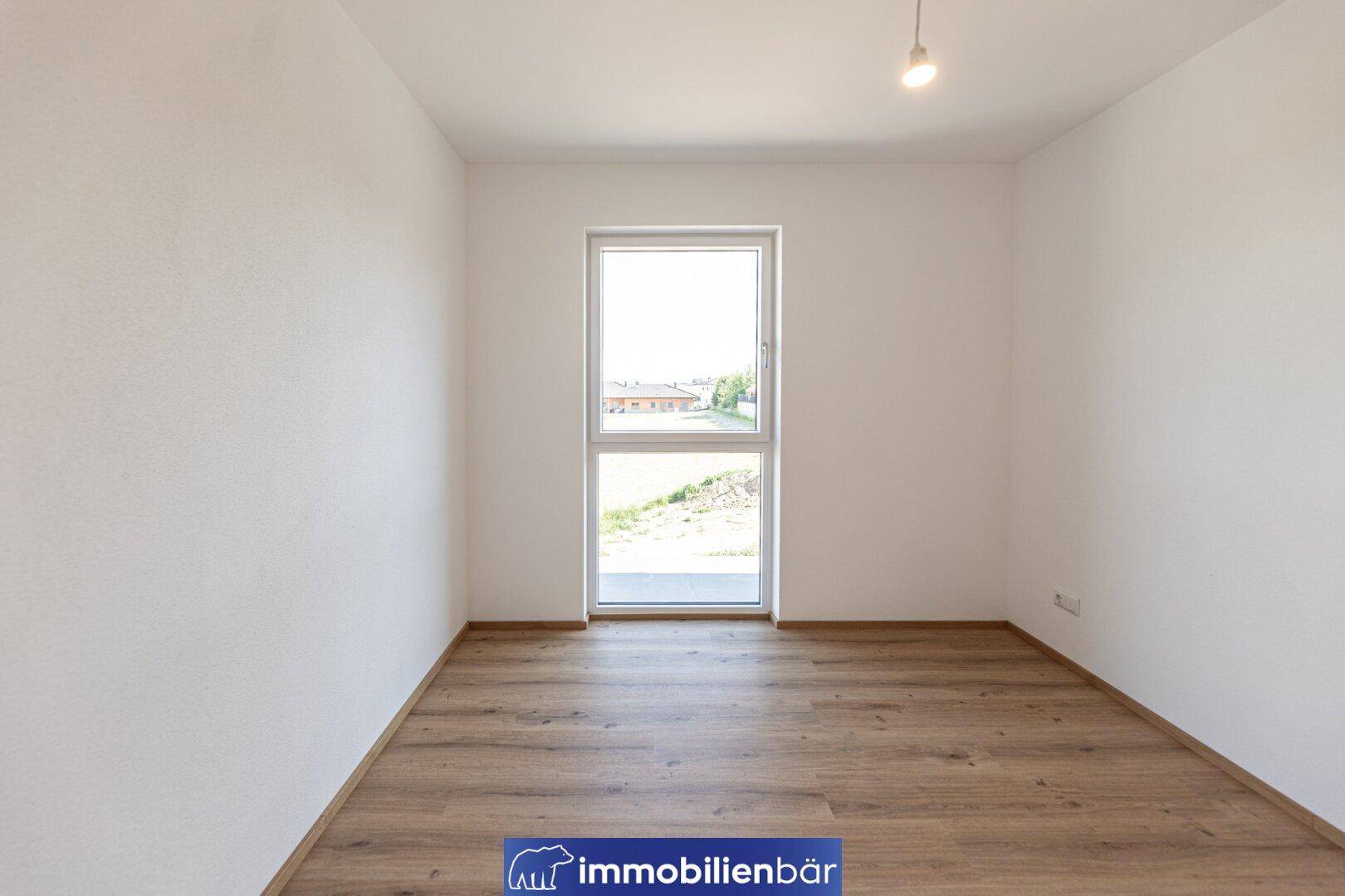 Geräumiges Zimmer mit Laminatboden und bodentiefem Fenster für viel Tageslicht.