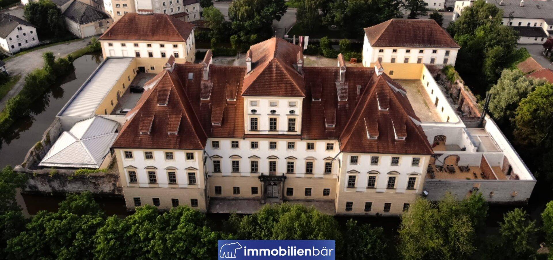 Detaillierte Luftaufnahme des historischen Gebäudes mit seiner imposanten Fassade und den umliegenden Grünflächen.