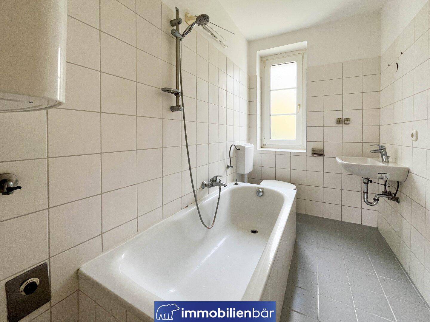 Badezimmer mit Badewanne, Waschbecken, WC und weiß gefliesten Wänden.