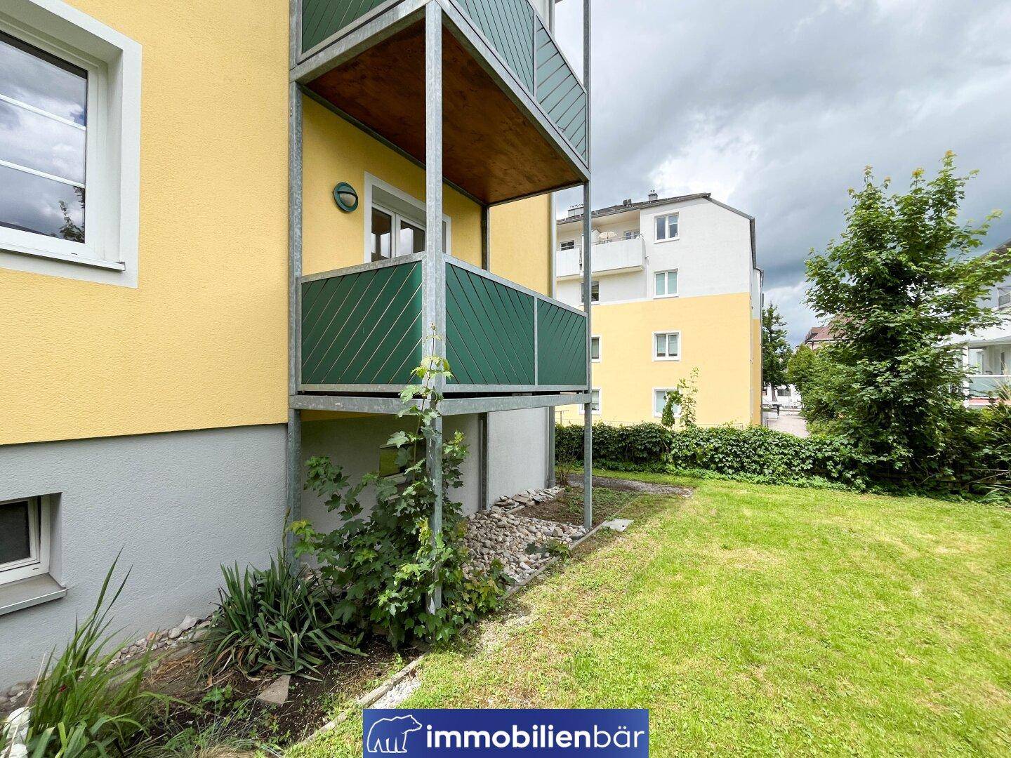 Gebäudeansicht mit Rasenfläche im Vordergrund und Balkonen an der Fassade.