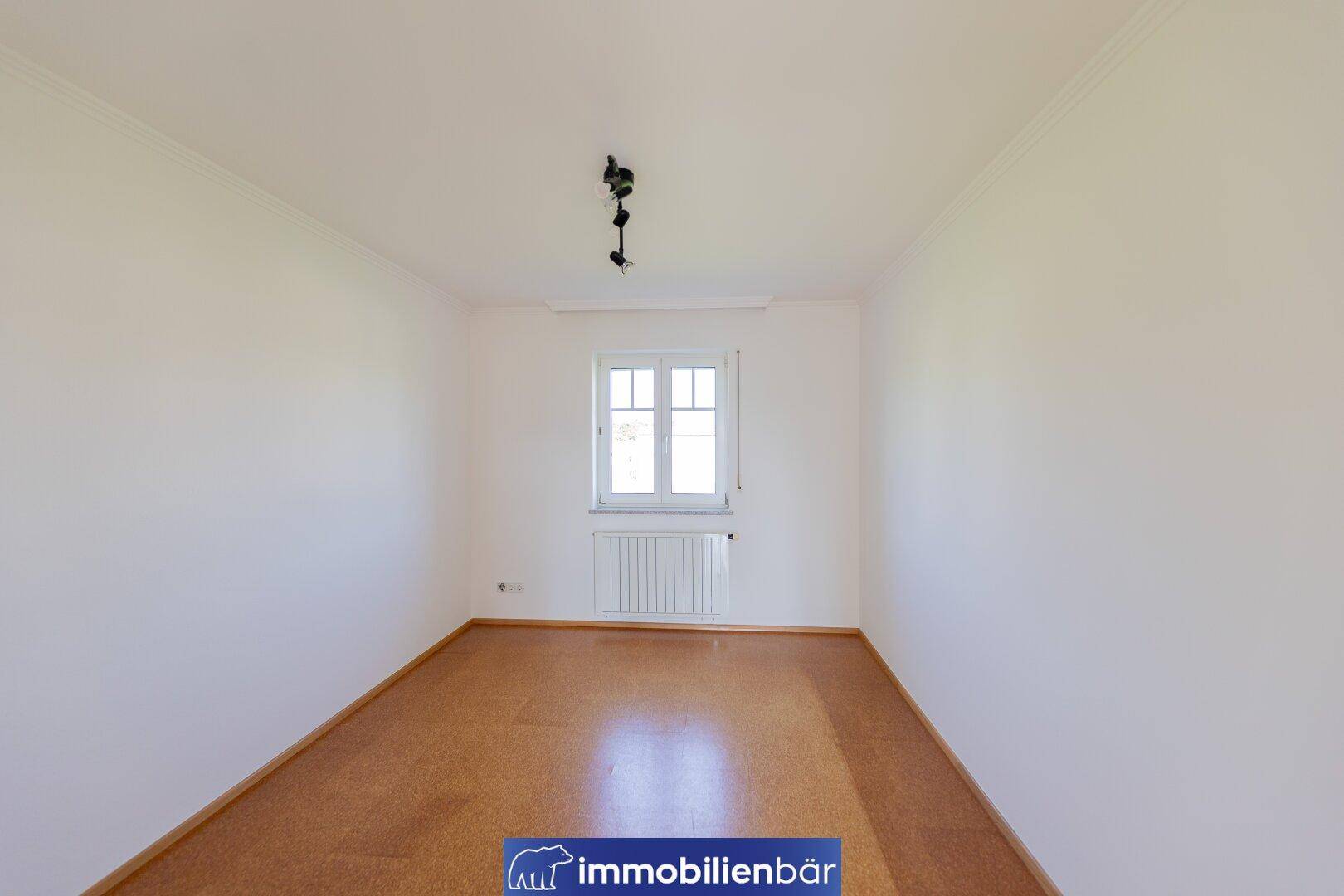 Ruhiges Schlafzimmer mit Korkboden und einem Fenster, ideal für Erholung.