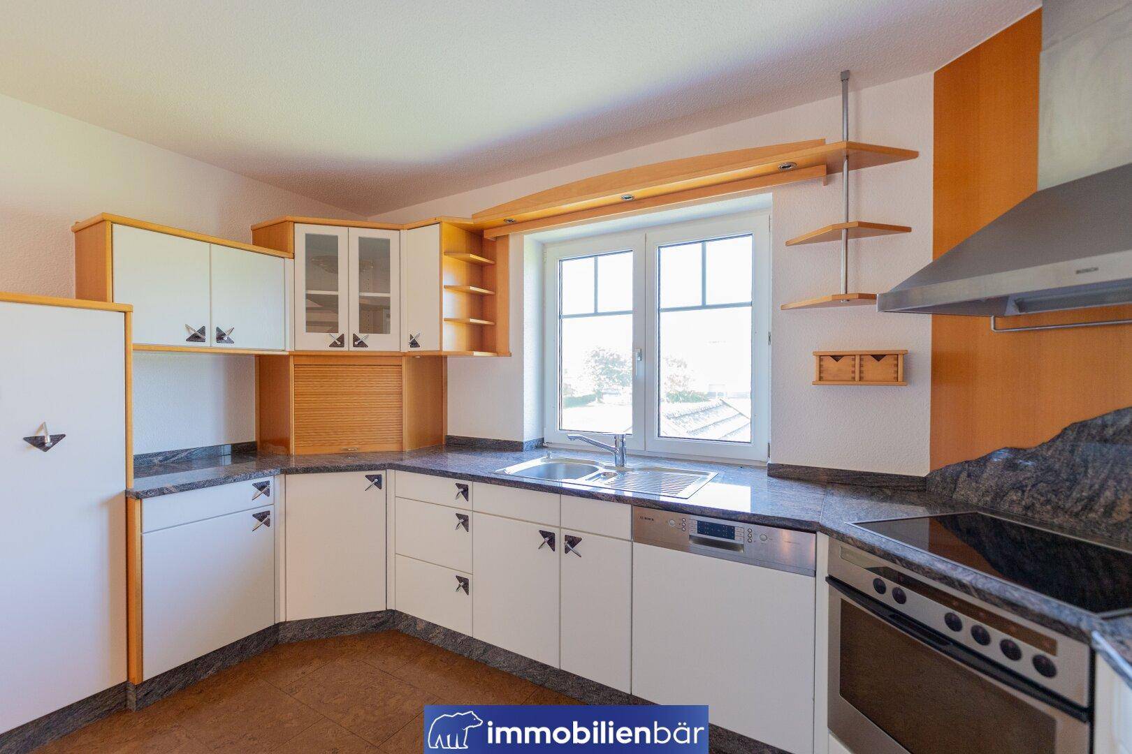 Funktionale Küche mit hellen Schränken, Granitarbeitsplatte und Fenster mit Ausblick.