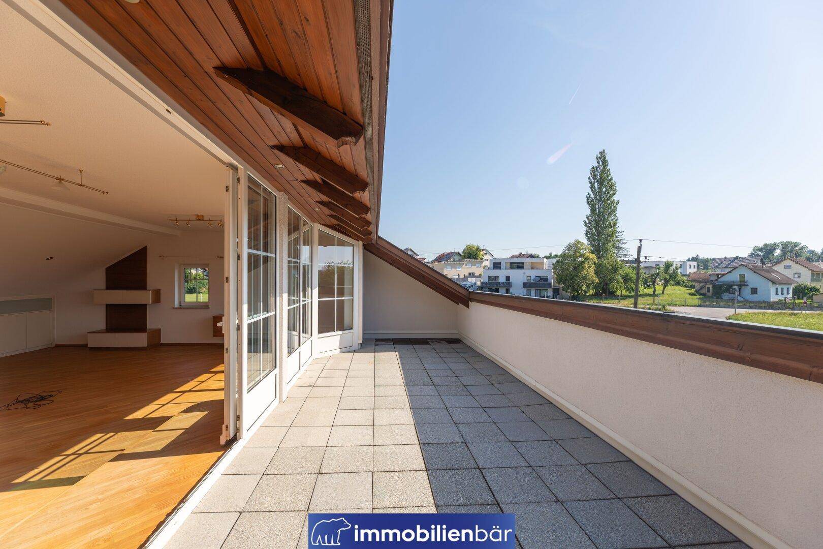 Große Dachterrasse mit Fliesenboden und Holzdach, bietet weite Aussicht.