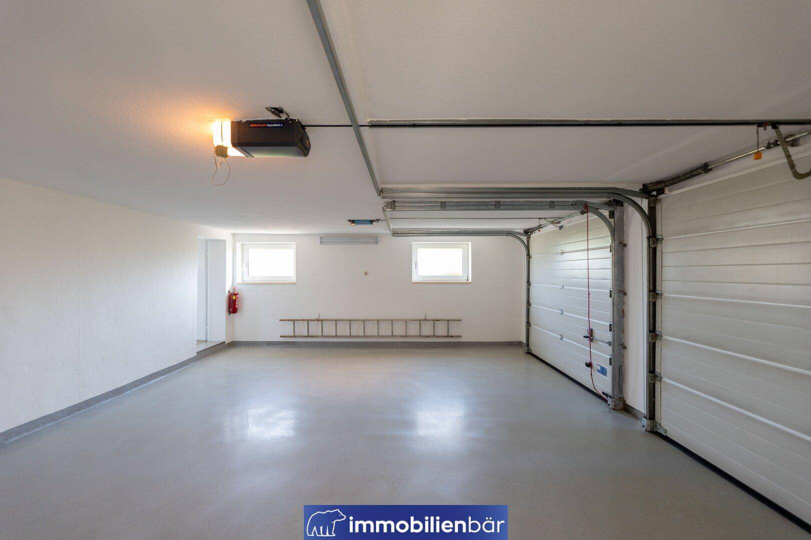 Geräumige Doppelgarage mit automatischem Tor, Fenstern und glattem Betonboden, in sehr gutem Zustand.