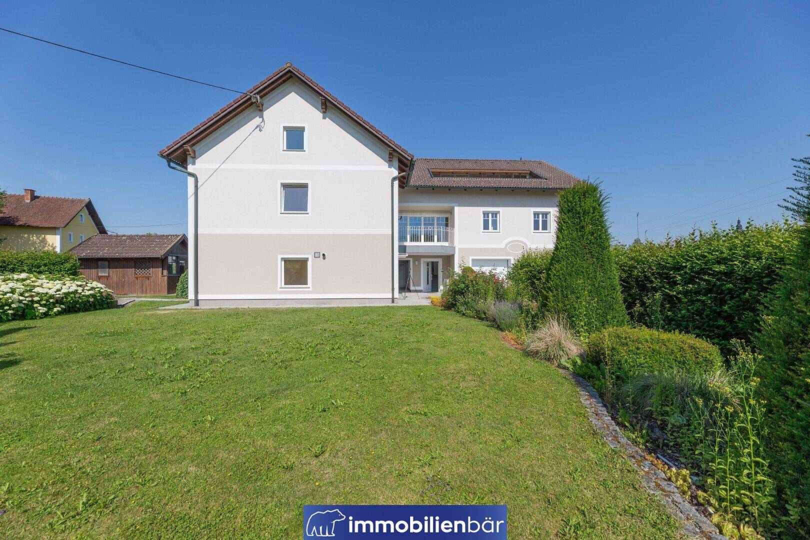 Seitenansicht des Hauses mit großem Gartenbereich und Blick auf die grüne Umgebung.