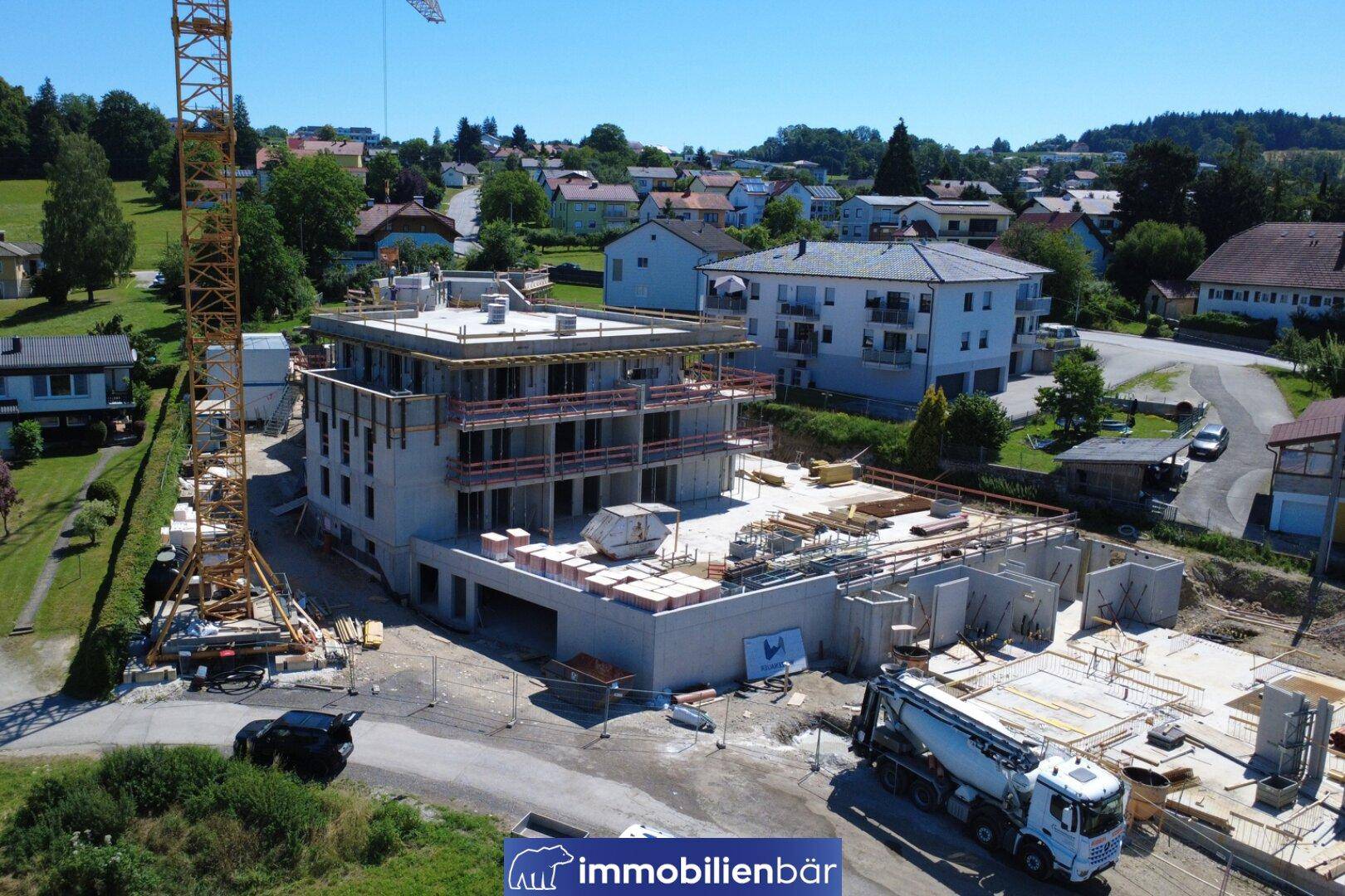 Luftaufnahme einer Baustelle mit einem im Bau befindlichen modernen Wohngebäude und Kran in ländlicher Umgebung.