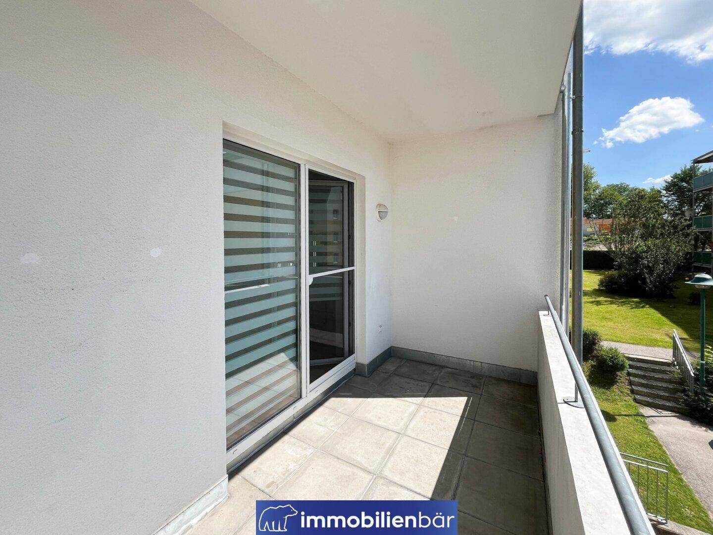 Heller Balkon mit Fliesenboden und Blick ins Grüne, ideal für entspannte Stunden im Freien.