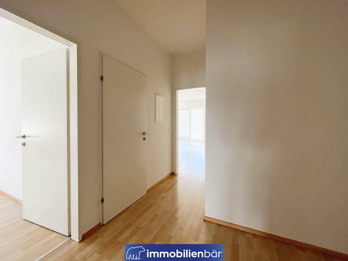 Heller Flur mit Parkettboden und weißen Türen, der verschiedene Räume der Wohnung verbindet.