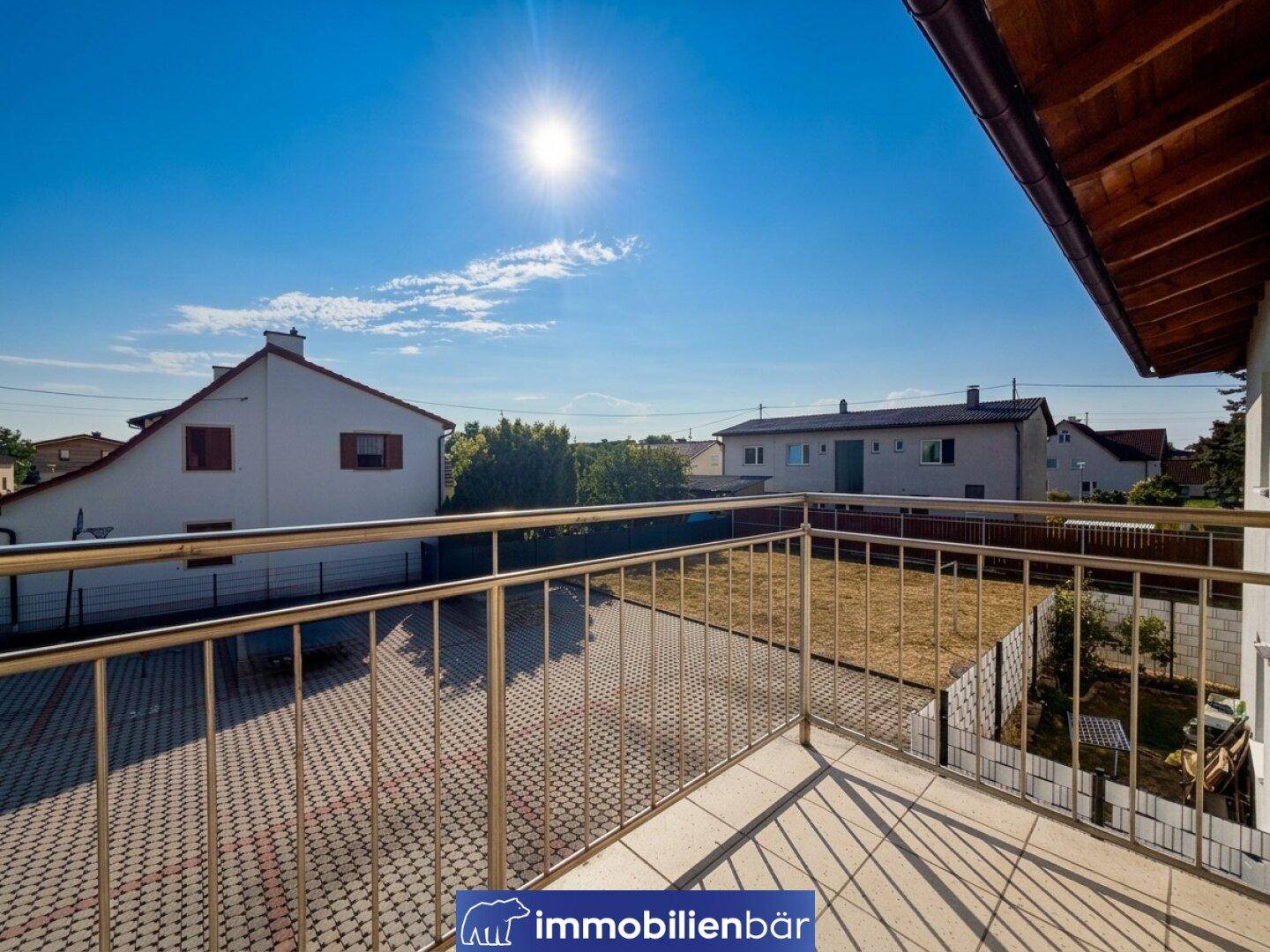 Geräumiger Balkon mit viel Sonnenlicht und weitem Blick über die Wohngegend und einen leeren Hof.