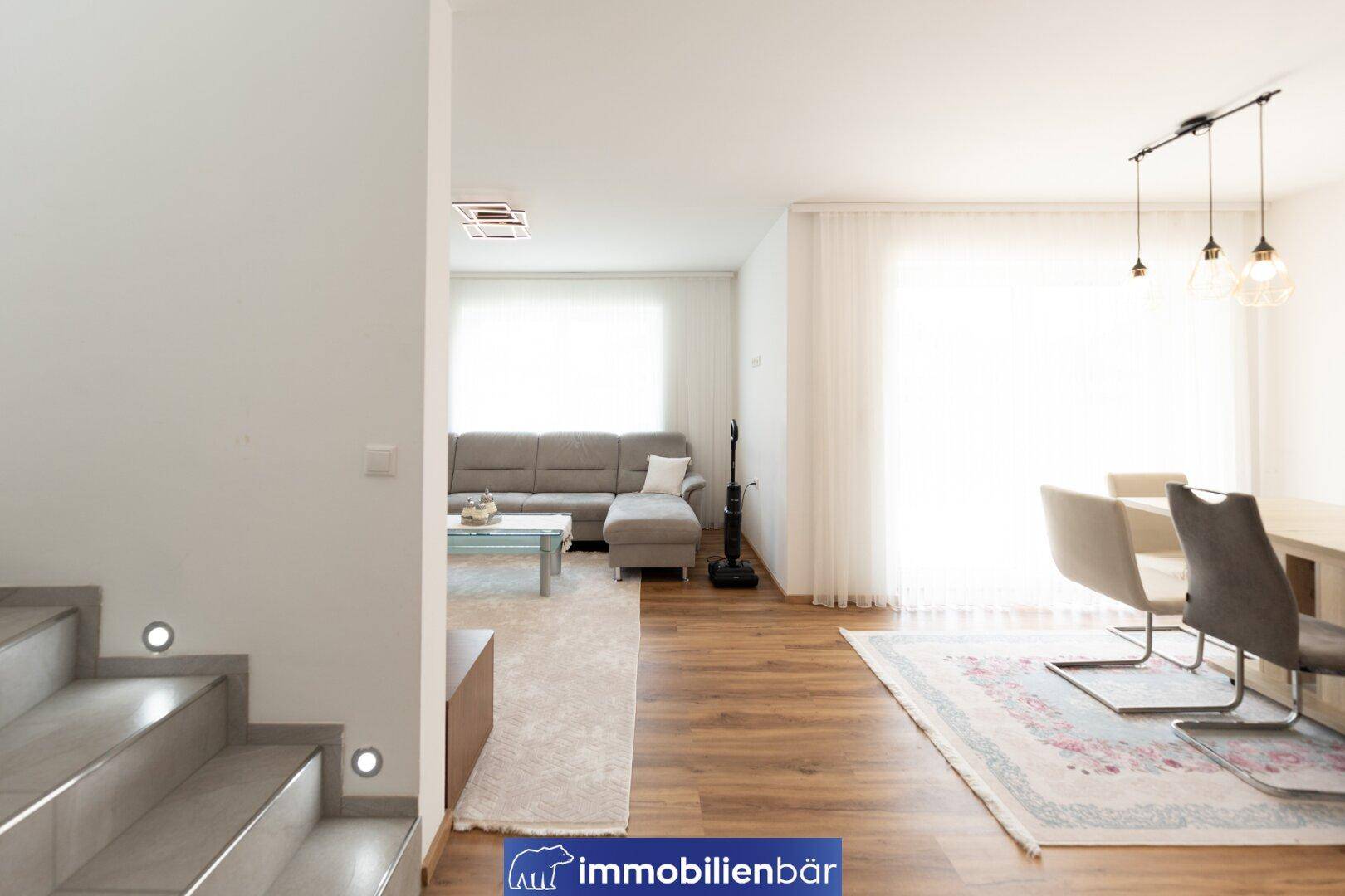 Offener Wohn- und Essbereich mit Laminatboden, viel Tageslicht und moderner Einrichtung.