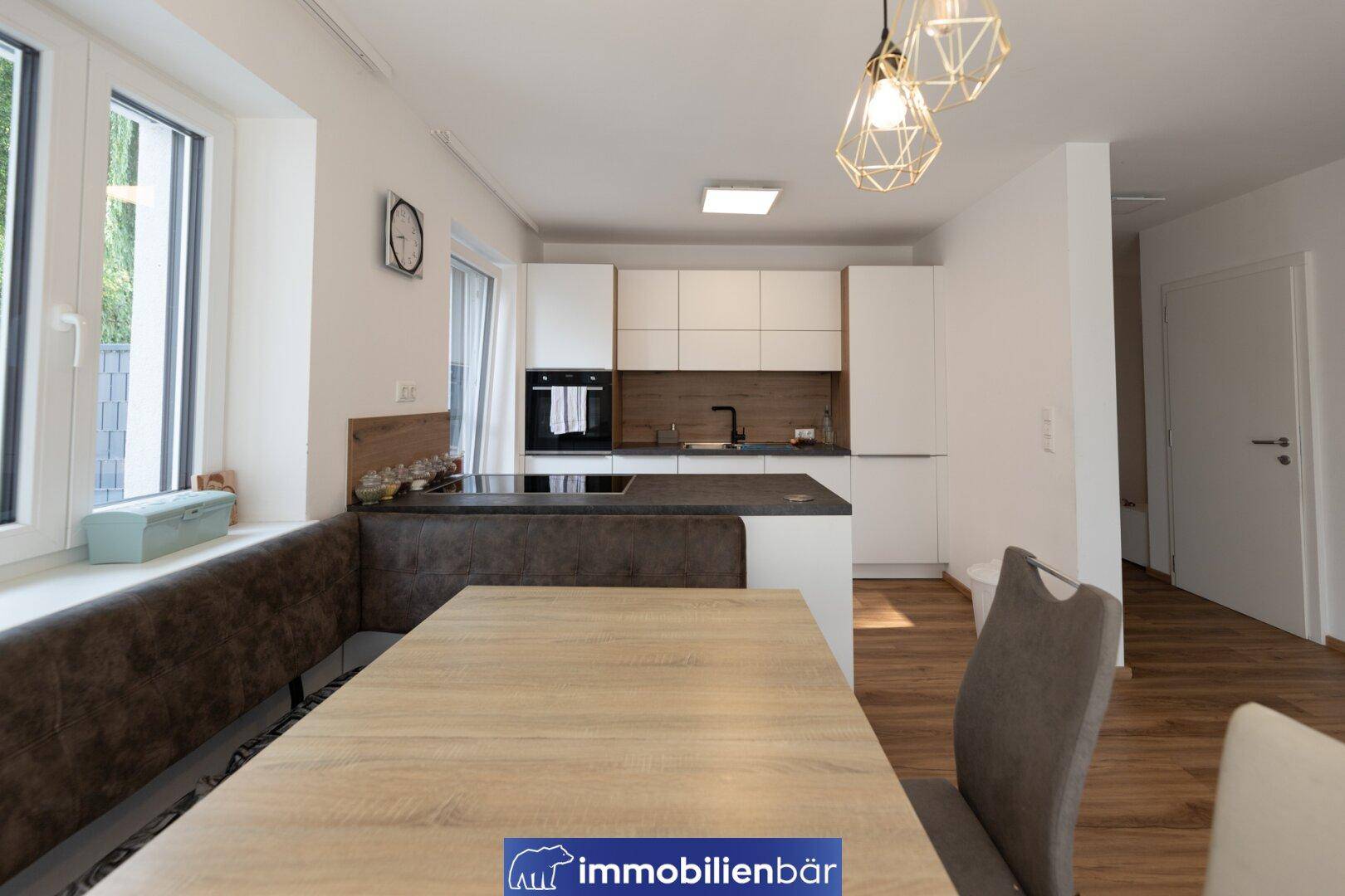 Moderne Einbauküche mit Essbereich, weißen Fronten und Holzdetails.