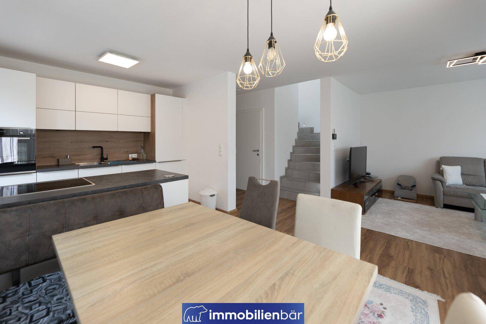 Heller Essbereich mit moderner Küche und offenem Übergang zum Wohnzimmer.