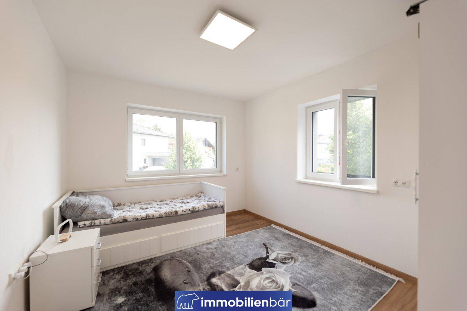 Helles Kinder- oder Gästezimmer mit Einzelbett, Fenster und Laminatboden.