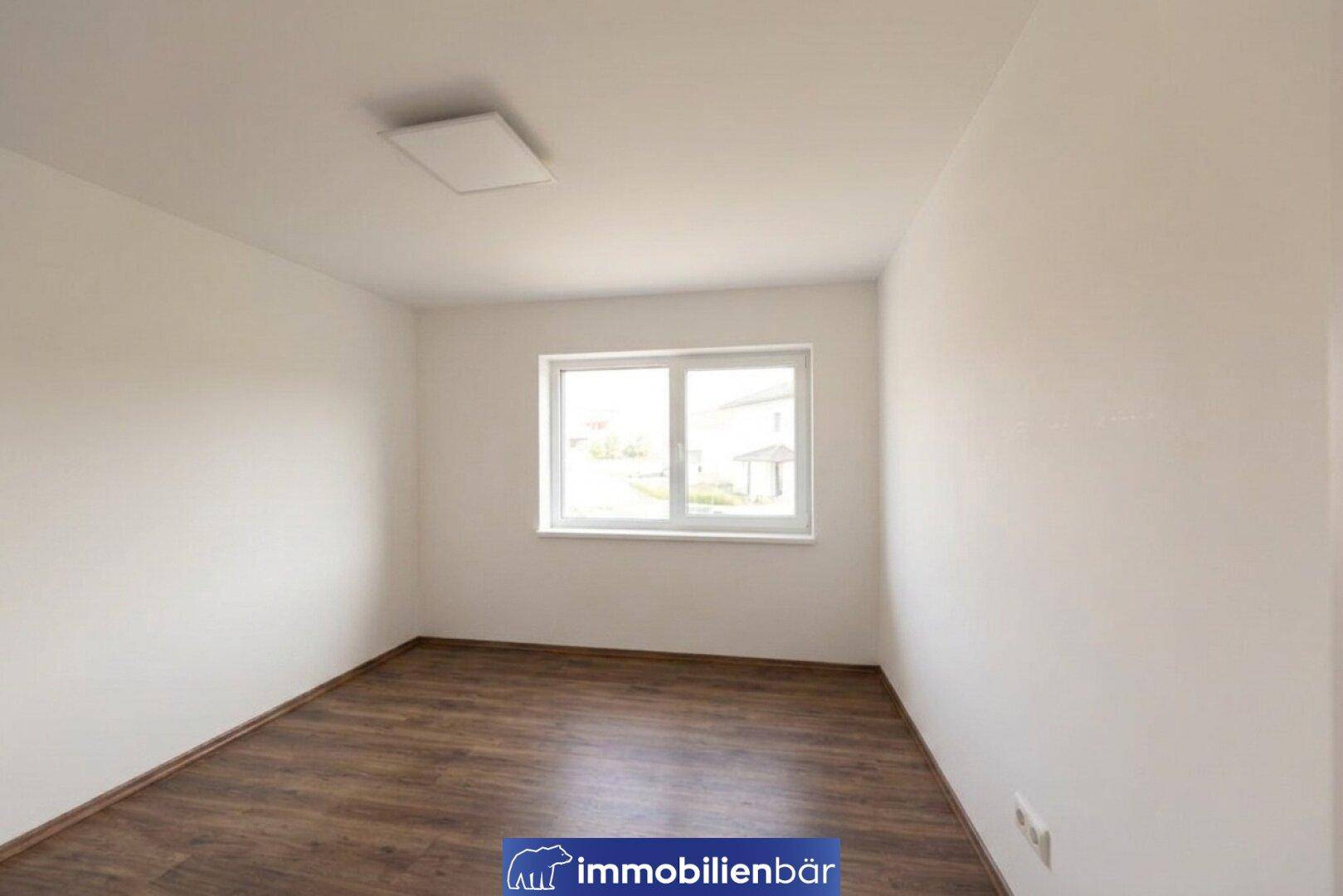 Leeres Schlafzimmer mit Laminatboden und einem Fenster, bereit zur individuellen Gestaltung.