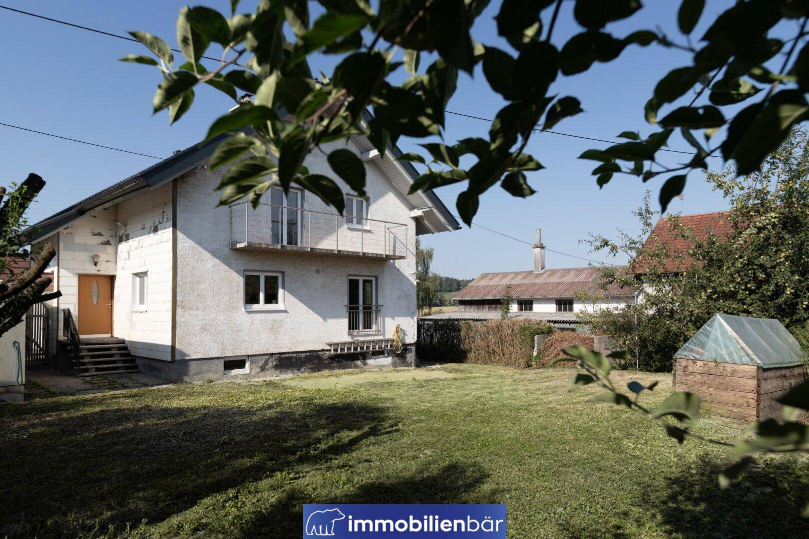 Seitenansicht des Hauses mit Garten, Obstbäumen und Blick auf die ländliche Umgebung.