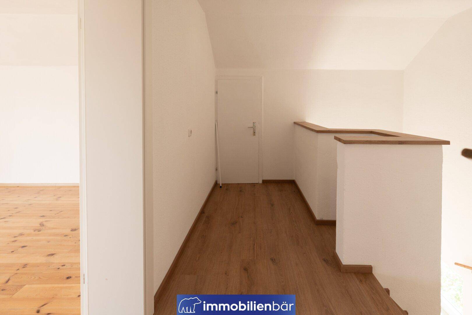 Heller Flur im Obergeschoss mit Laminatboden und Zugang zu weiteren Zimmern.