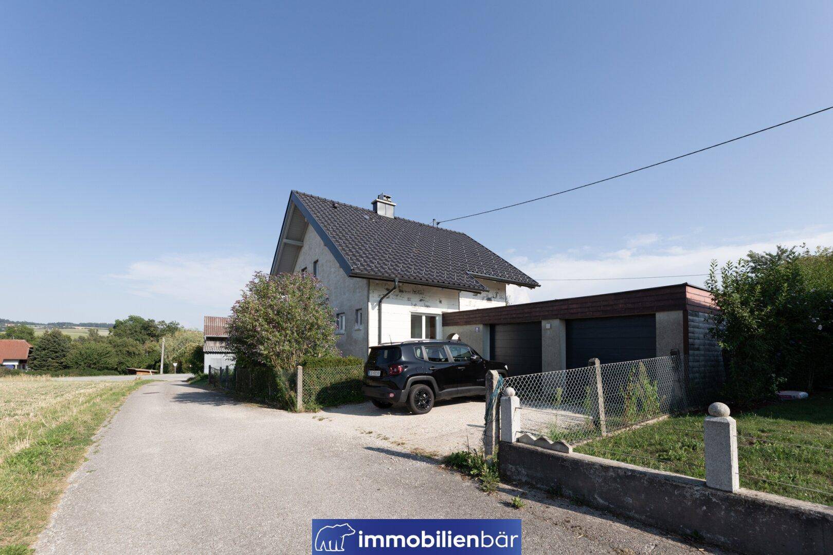 Ansicht des Einfamilienhauses von der Straße mit Doppelgarage und Stellplatz.