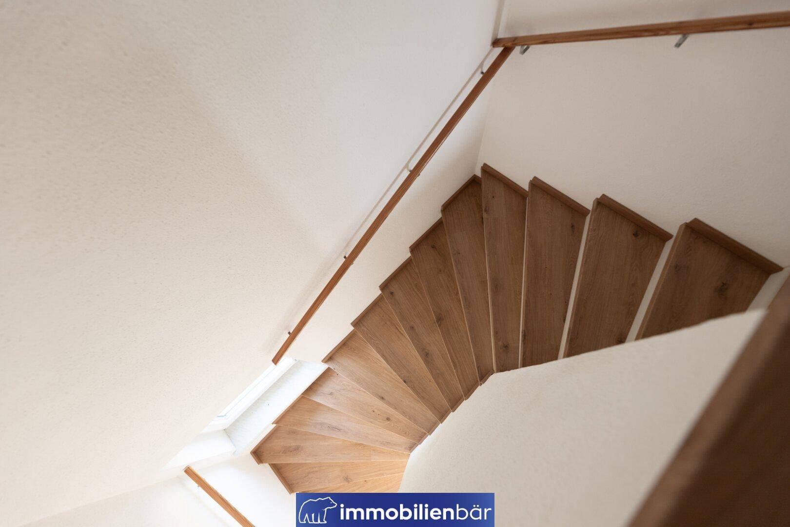 Holztreppe mit hellem Geländer, die die Stockwerke des Hauses miteinander verbindet.