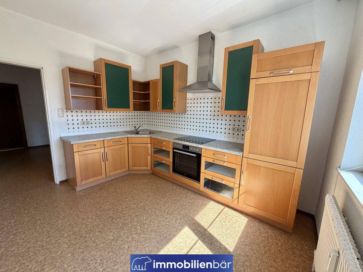 Geräumige Küche mit hellen Holzfronten, integrierten Geräten und praktischer Arbeitsfläche.