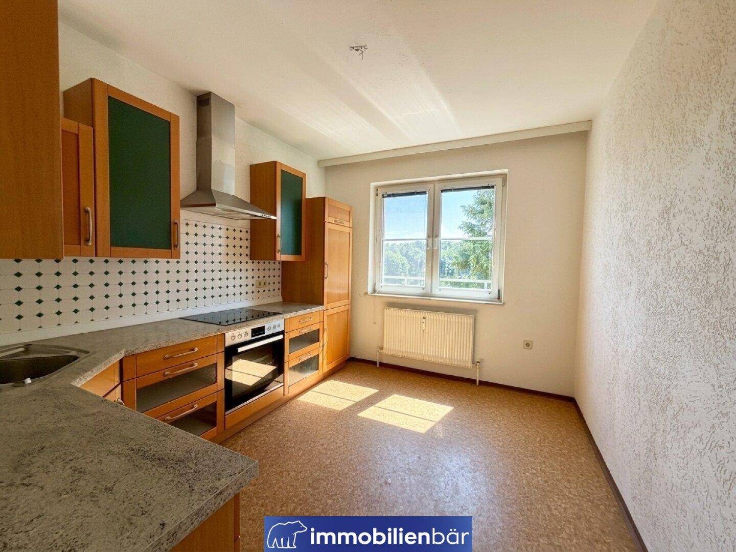 Funktionale Küche mit Holzschränken, grünen Akzenten und einem Fenster mit Ausblick.