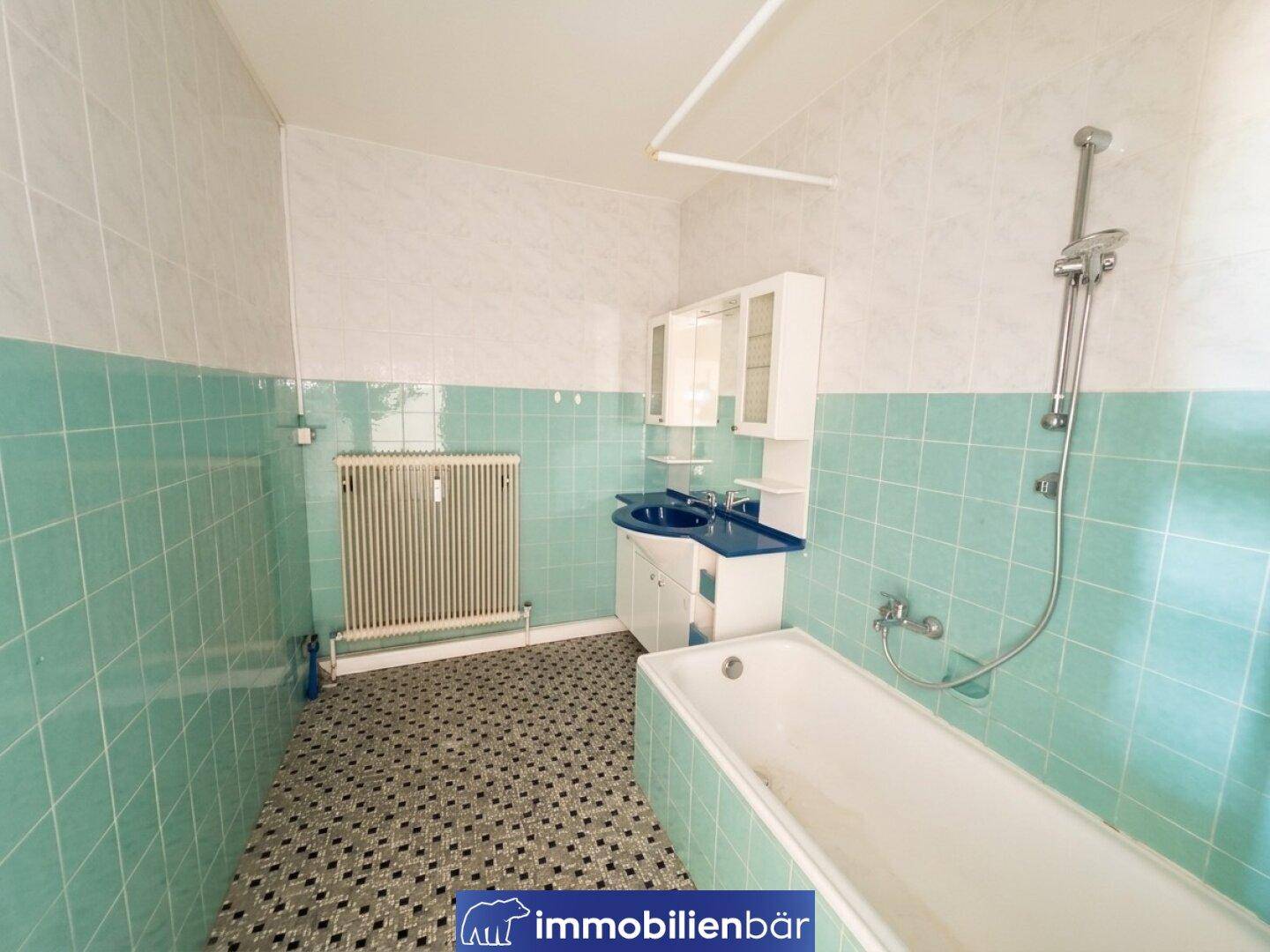 Badezimmer im Stil der 80er Jahre mit mintgrünen Fliesen, Badewanne und Waschbecken.