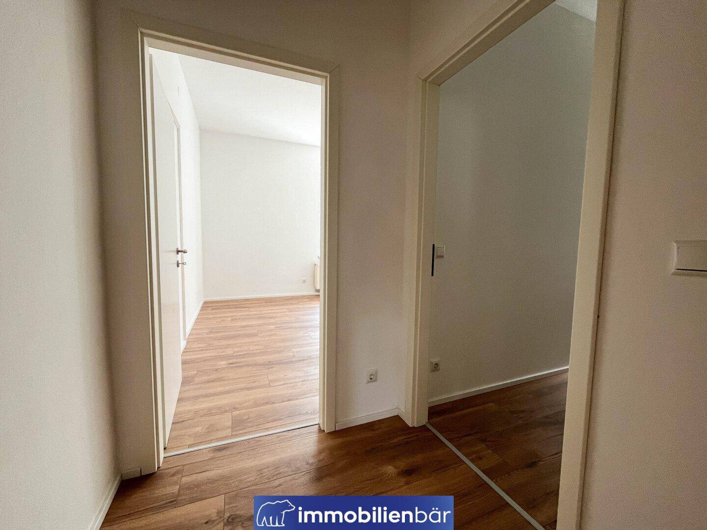 Heller Flur mit Laminatboden, der zu weiteren Zimmern der Wohnung führt.