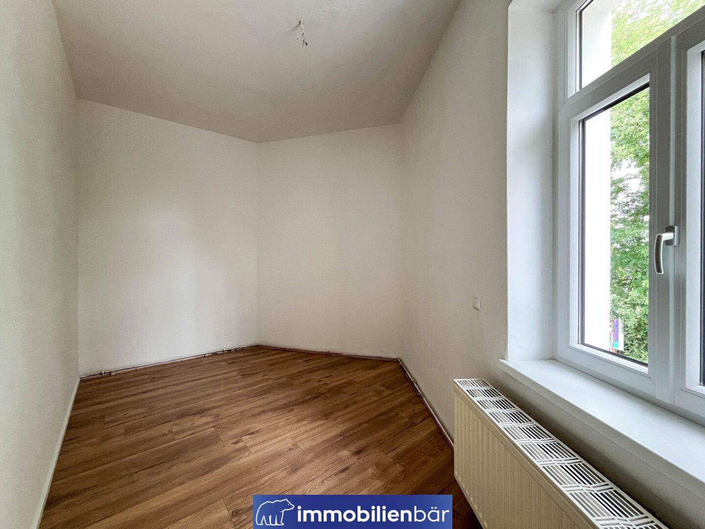 Kleineres, helles Zimmer mit Laminatboden und einem großen Fenster für viel Licht.