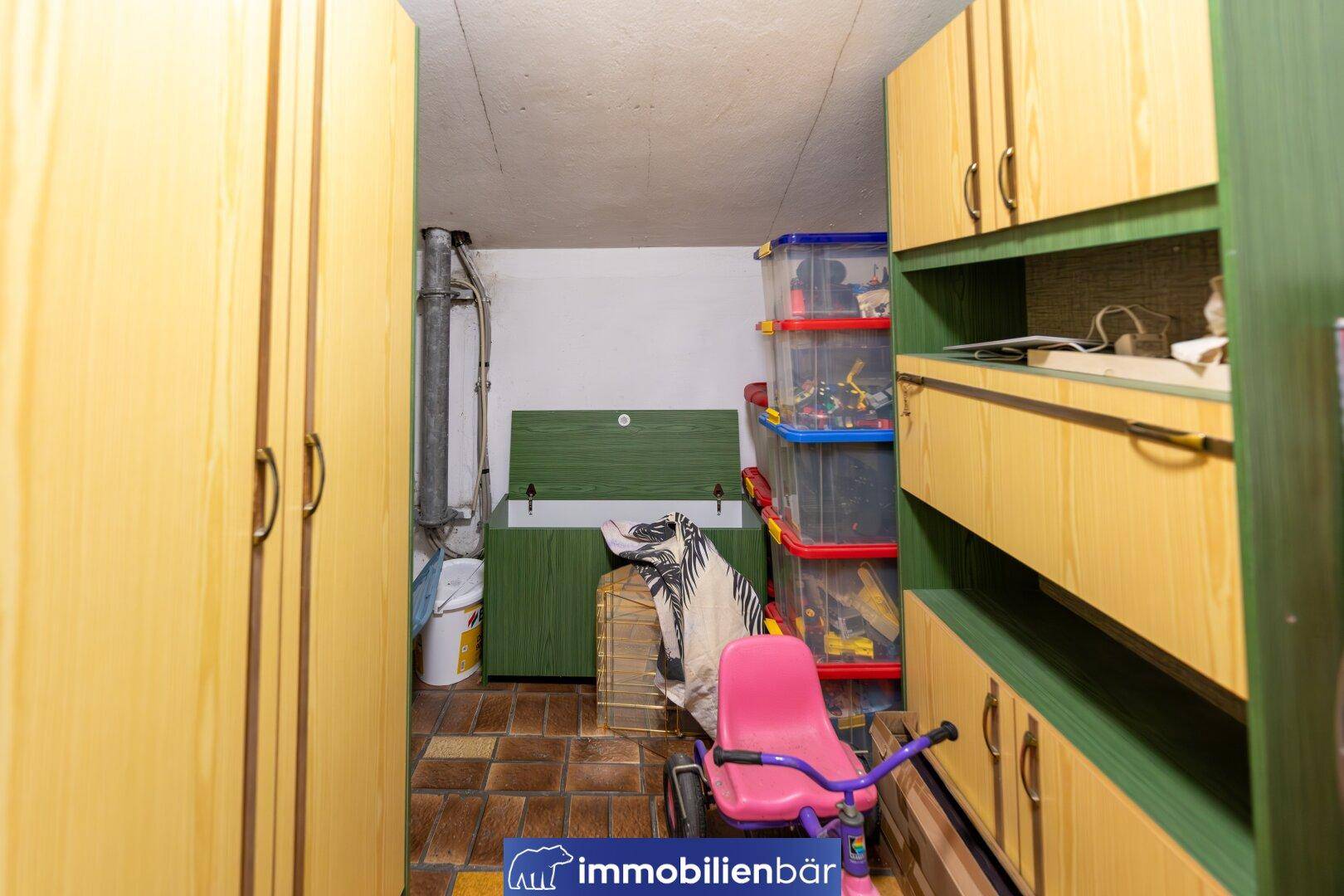 Praktischer Abstellraum mit Holzschränken, Regalen und Stauraum für verschiedene Gegenstände im Keller.