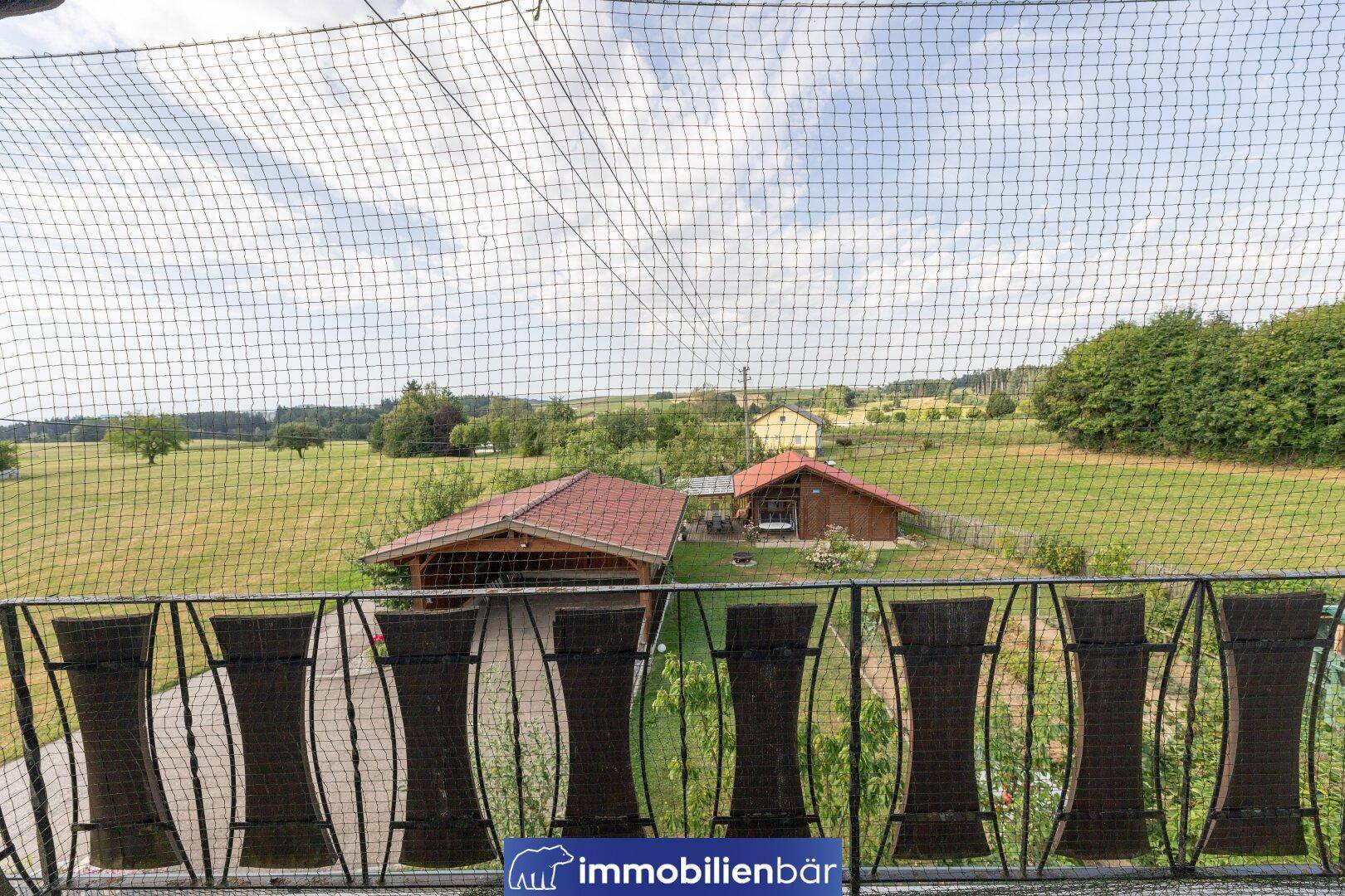 Blick vom Balkon über eine weite grüne Landschaft mit Feldern und Bäumen.