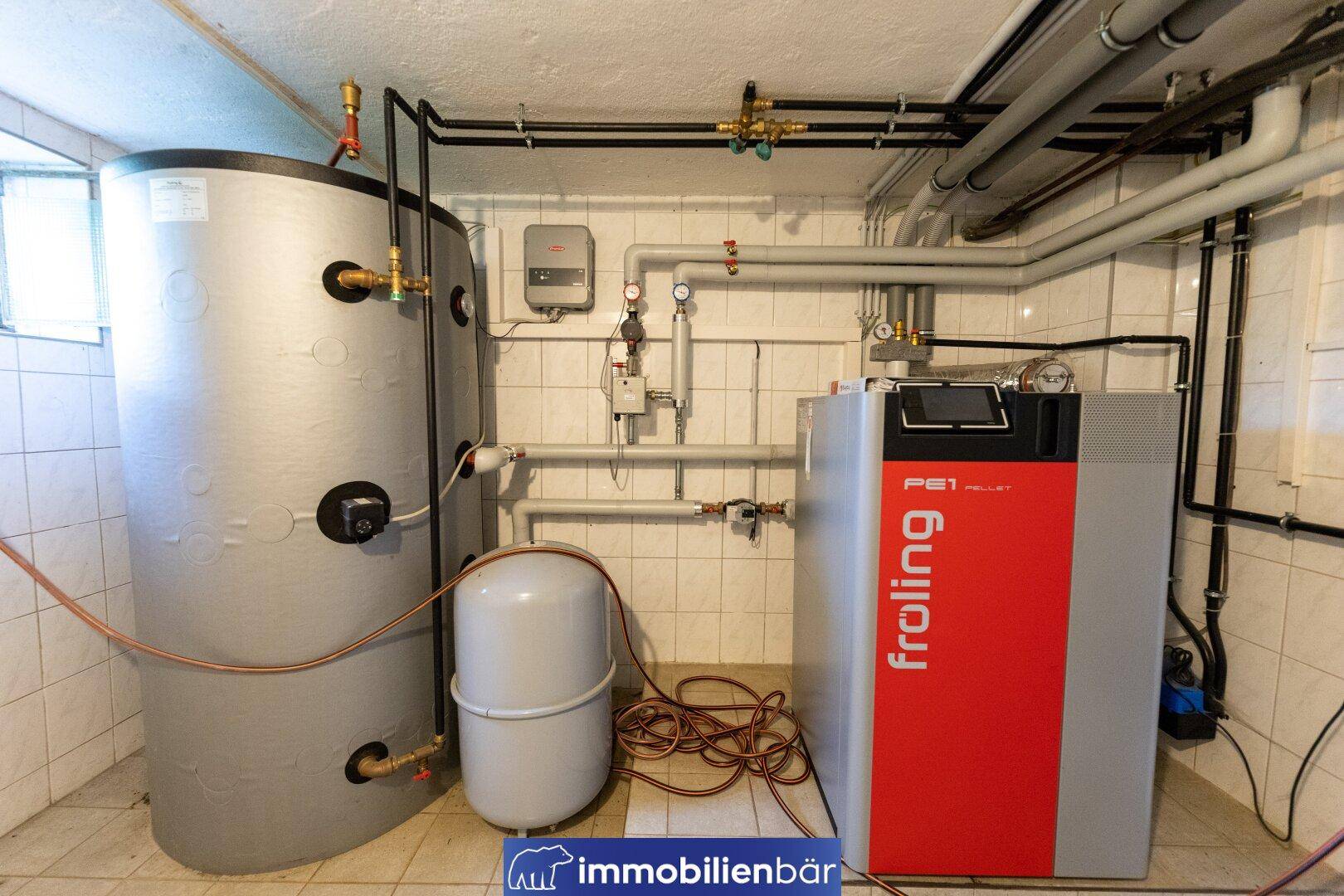 Heizraum mit modernem Froling Pelletkessel und großem Warmwasserspeicher.