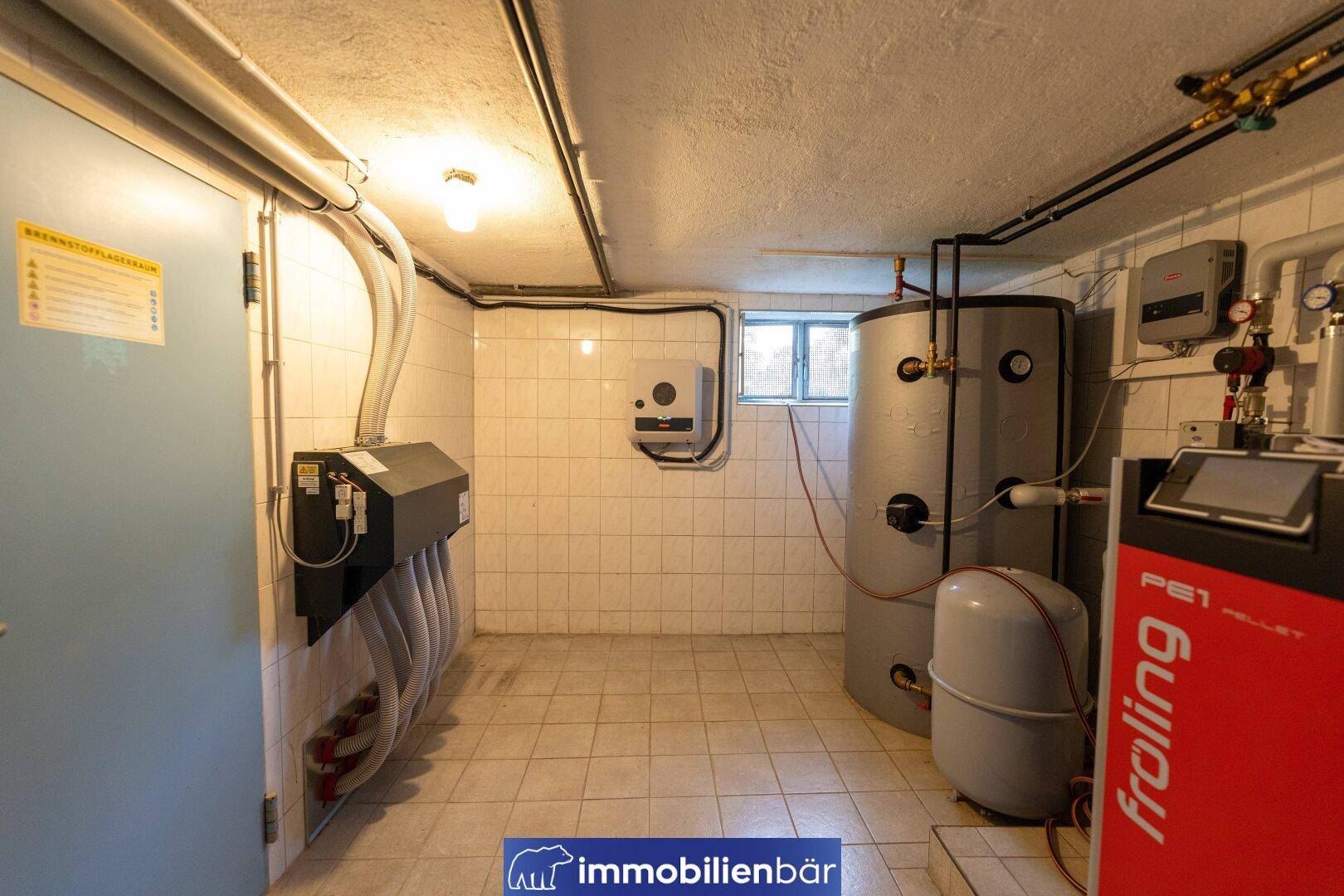 Geräumiger Heizraum mit gefliesten Wänden, kleinem Fenster und moderner Heizungsanlage.