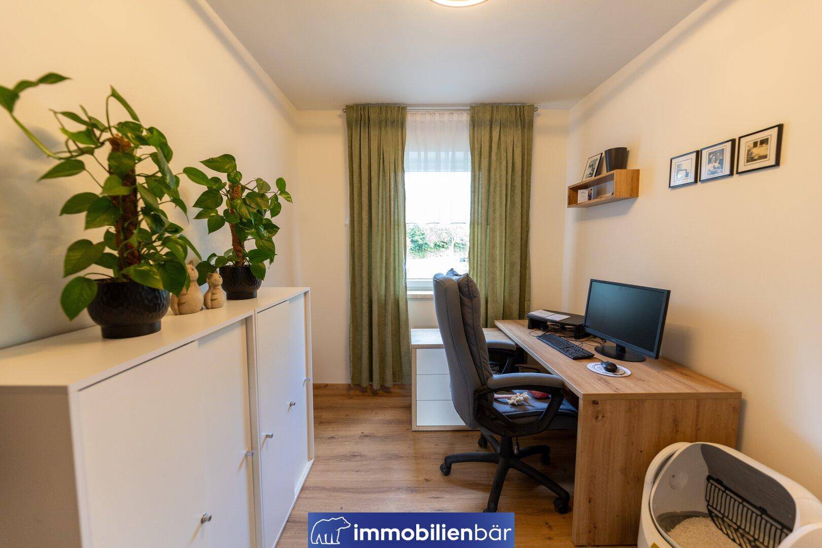 Helles Arbeitszimmer mit Holzschreibtisch, Bürostuhl und Pflanzen am Fenster, ideal für Homeoffice.