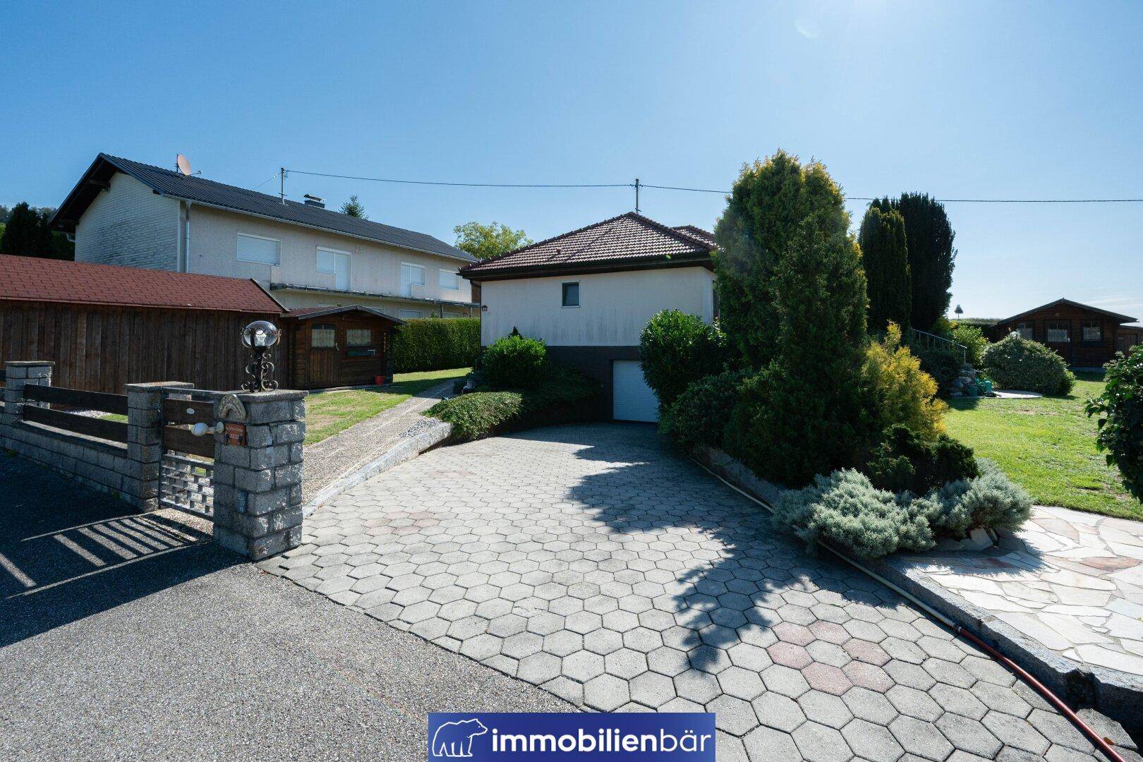 Einfahrt zum Haus mit gepflastertem Bereich und Zugang zur Garage im Untergeschoss.