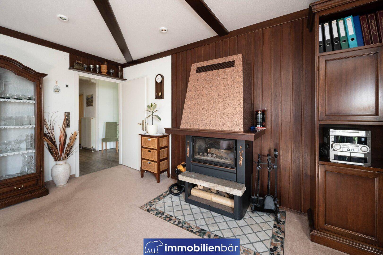 Gemütliches Wohnzimmer mit Kamin, Holzvertäfelung und Teppichboden, traditionell eingerichtet.