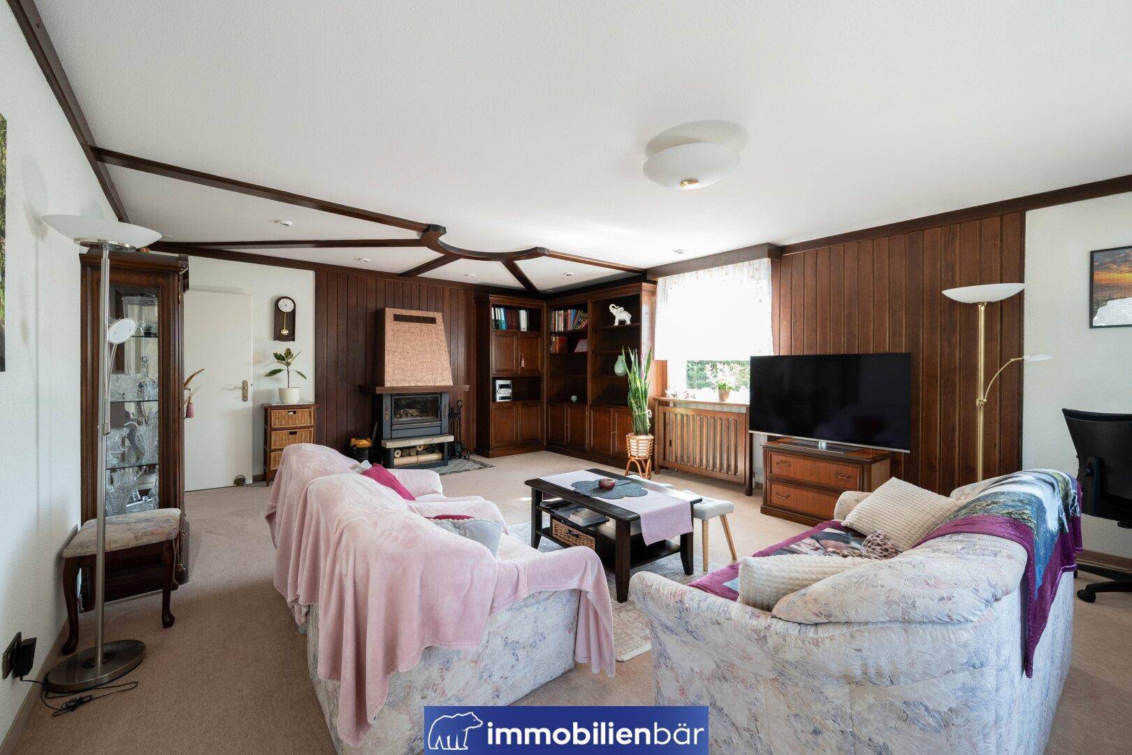Geräumiges Wohnzimmer mit Kamin, Holzvertäfelung und bequemen Sofas, traditioneller Stil.