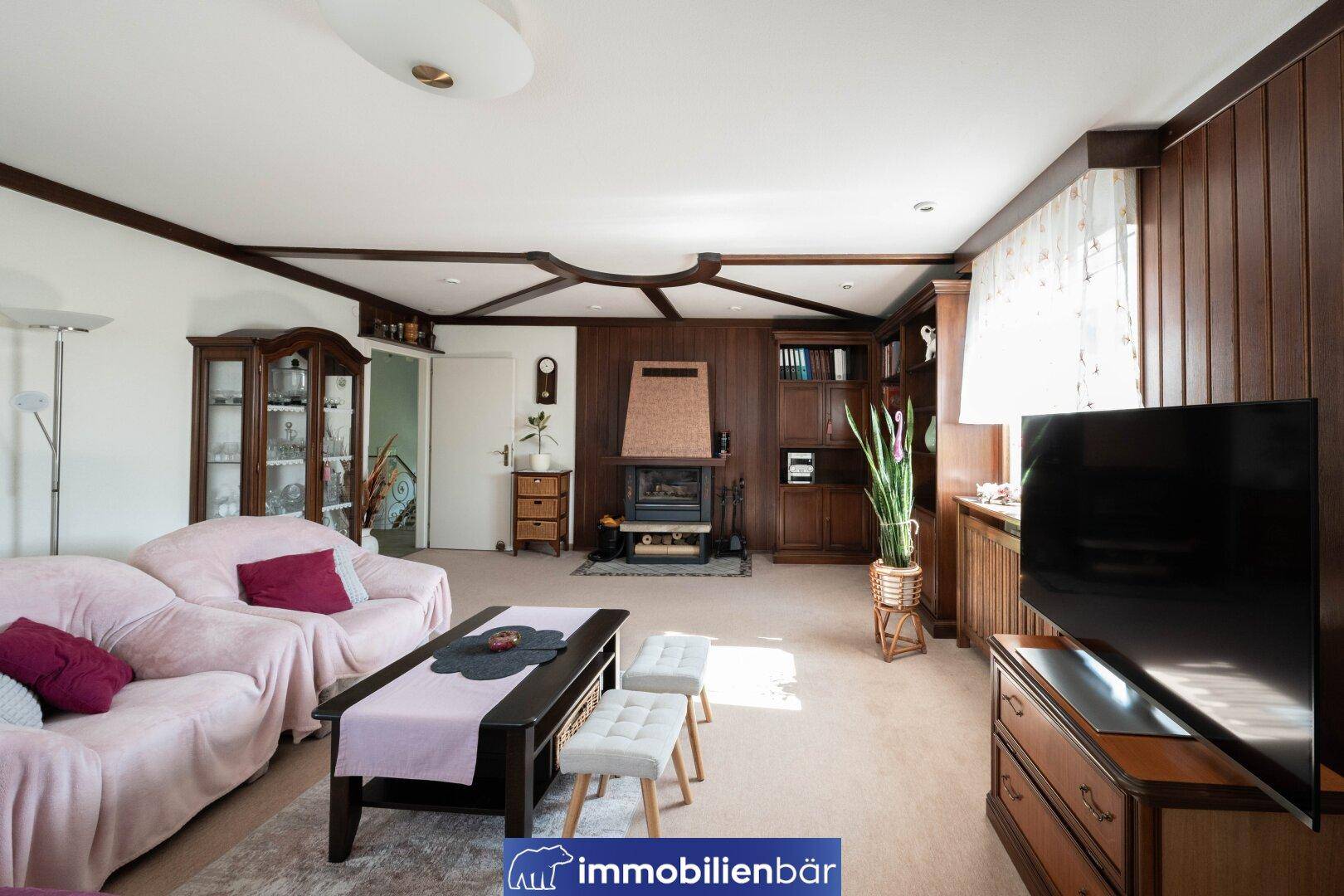 Gemütliches Wohnzimmer im traditionellen Stil mit Holztäfelung, Kamin und bequemen Sofas.